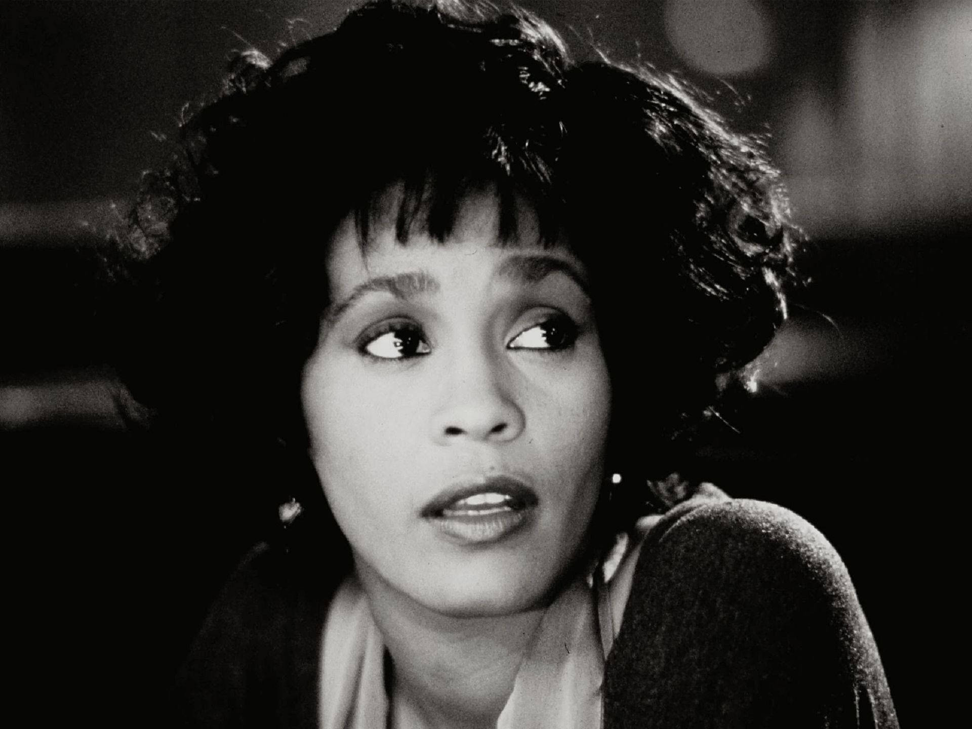 Whitney 桌布 壁紙 — 一個黑白特寫，一位捲髮女性向上看，表情豐富。