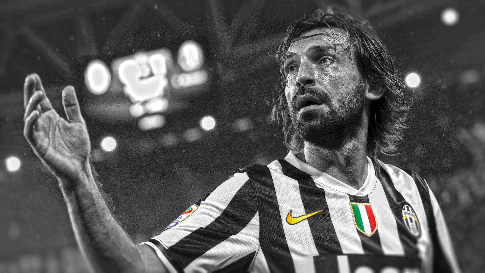 andrea pirlo 桌布 壁紙 — 一個黑白特寫，一名留鬍鬚的足球員穿著條紋球衣，在球場燈光下比賽時熱情地做手勢。