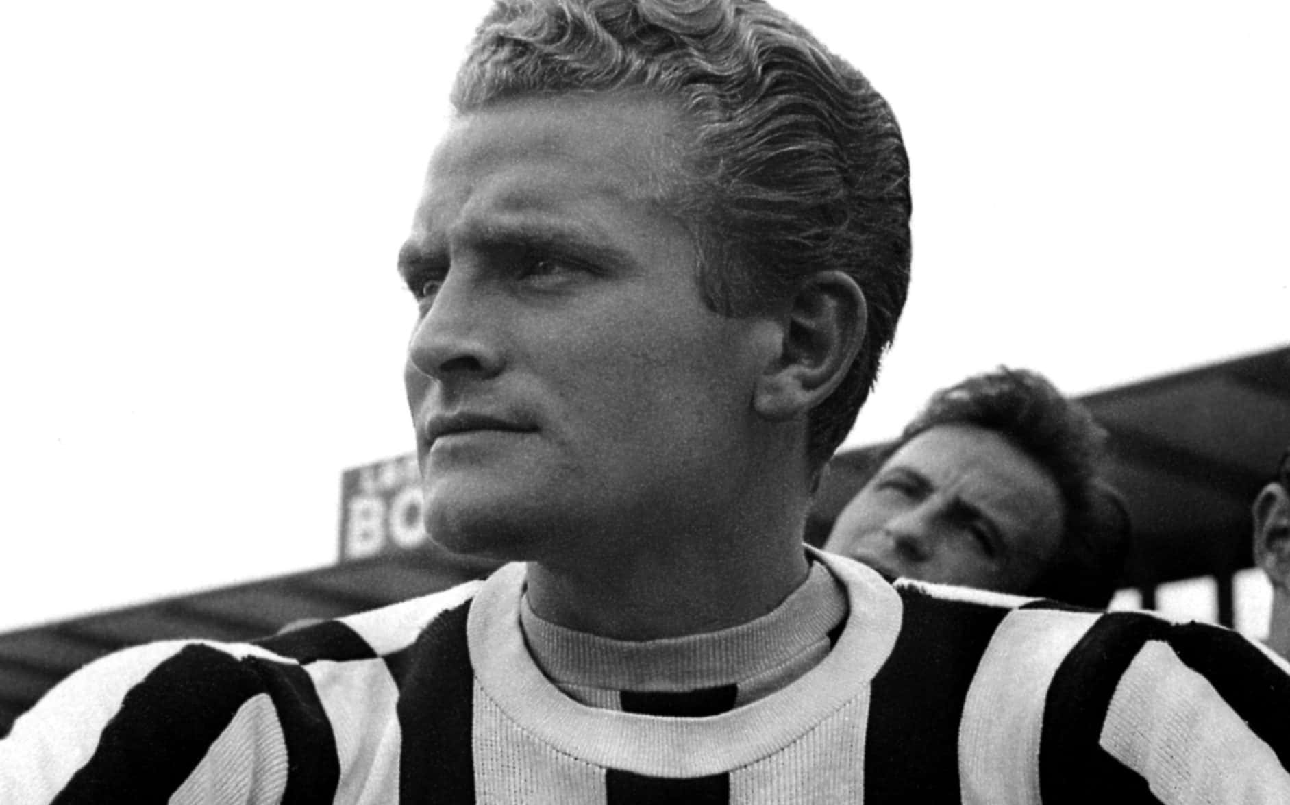 Football Players 桌布 壁紙 — 一個黑白特寫，聚焦於一位穿著條紋球衣的足球運動員，目光離開鏡頭，背景是體育場。