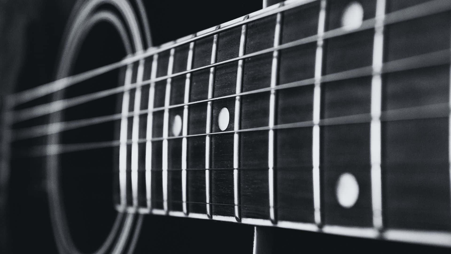 Black And White Guitar 桌布 壁紙 — 一個黑白特寫，聚焦於木吉他的指板，弦線和鑲嵌在深色背景下清晰可見。