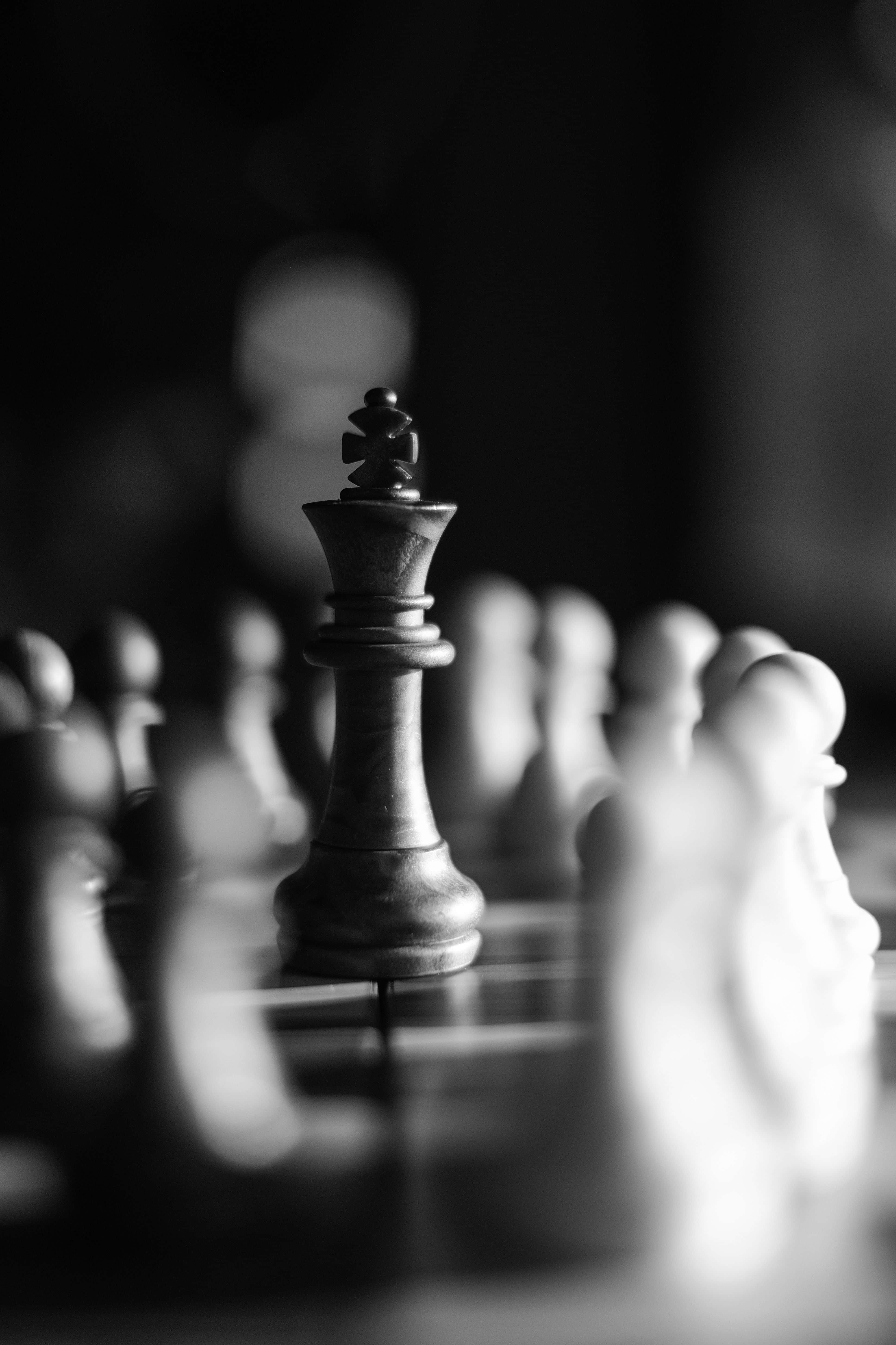Black And White Chess 桌布 壁紙 — 一個黑白特寫，顯示一枚西洋棋國王棋子高高立在棋盤上，背景有模糊的對手棋子。