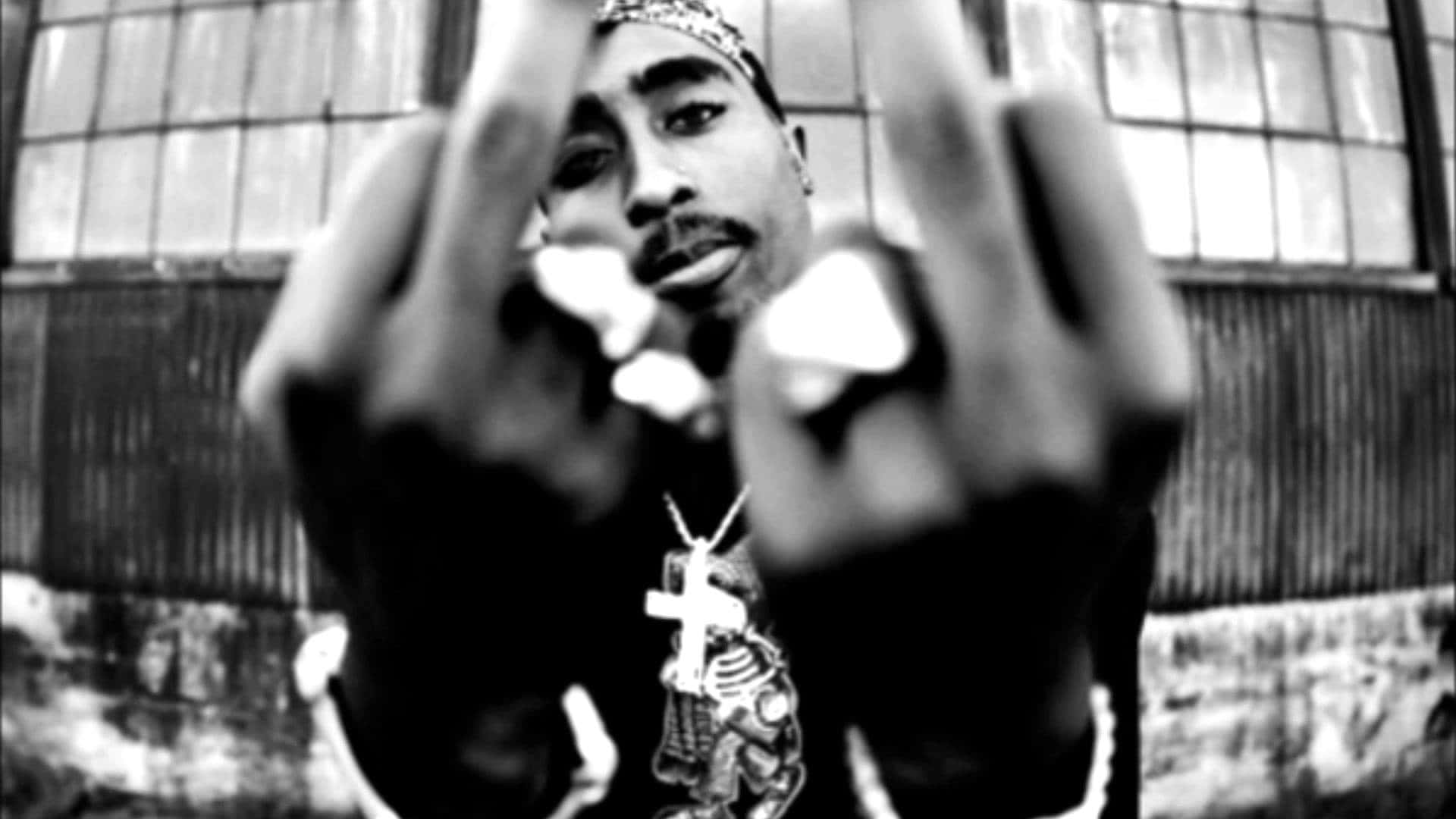 城市環境中男子戴十字架項鍊做手勢 — Tupac GIF 壁紙