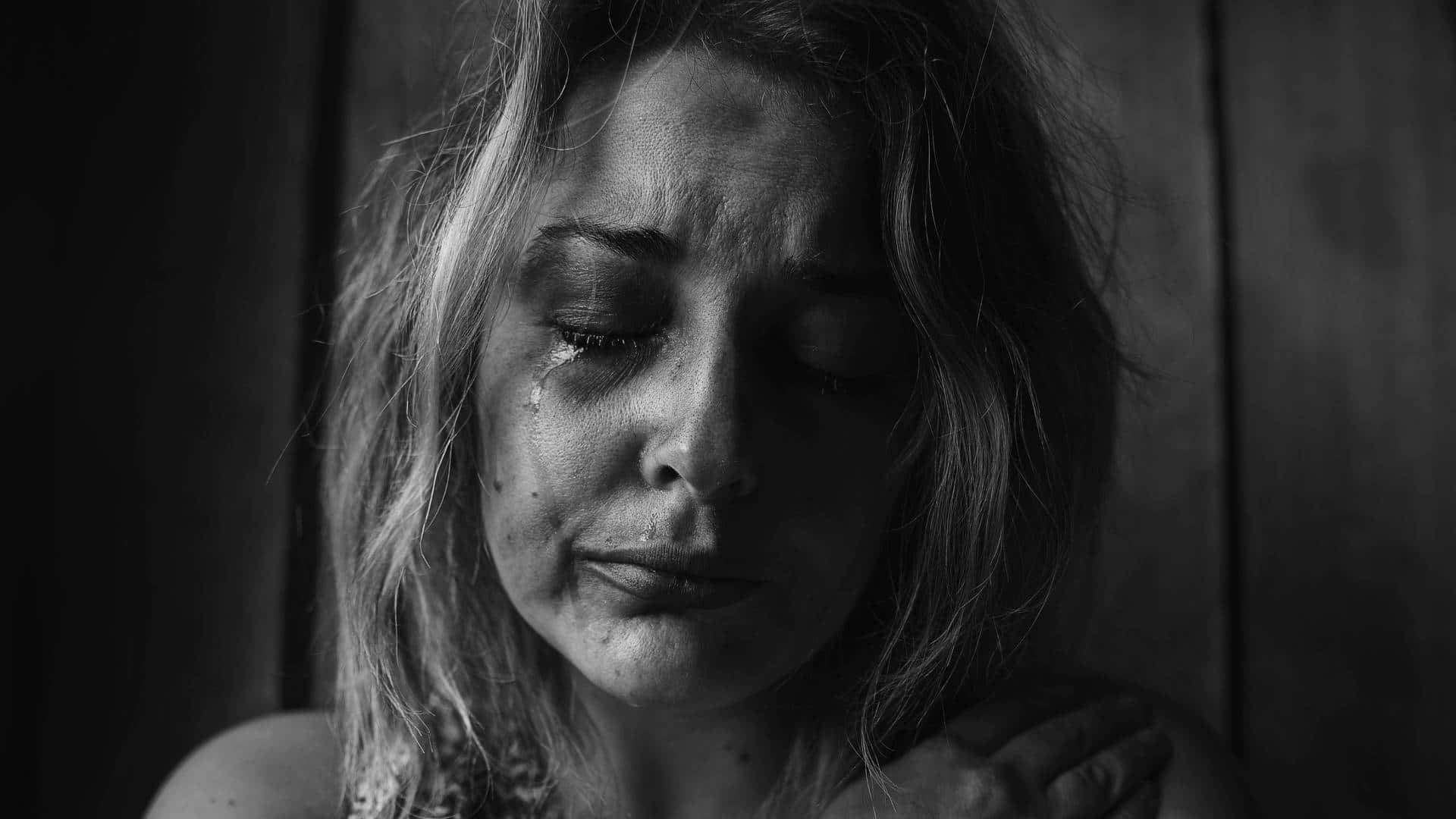 Dark Emotional 桌布 壁紙 — 一個黑白特寫鏡頭，捕捉一位女性悲傷地低頭，淚水順著臉頰流下。