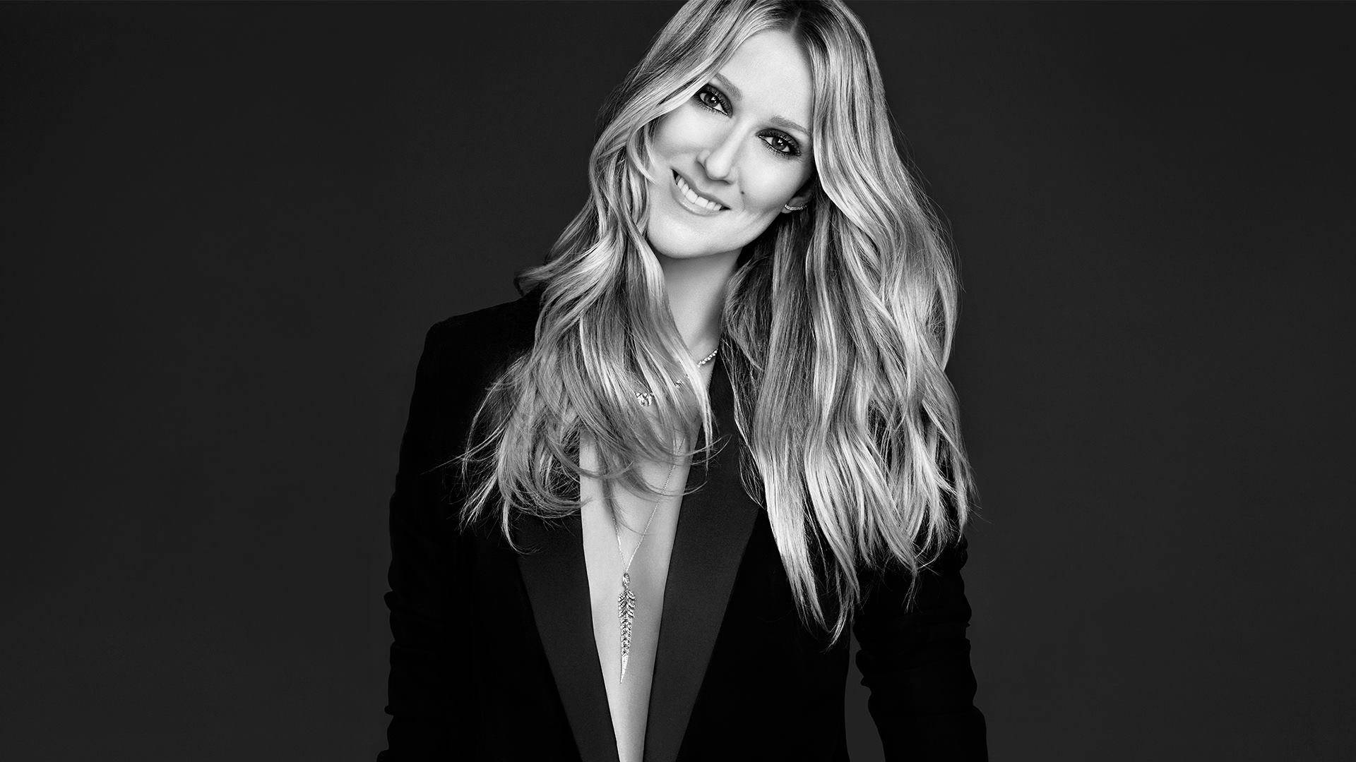 Celine 桌布 壁紙 — 一個黑白肖像，一位微笑的長波浪髮女性穿著西裝外套，背景深色。