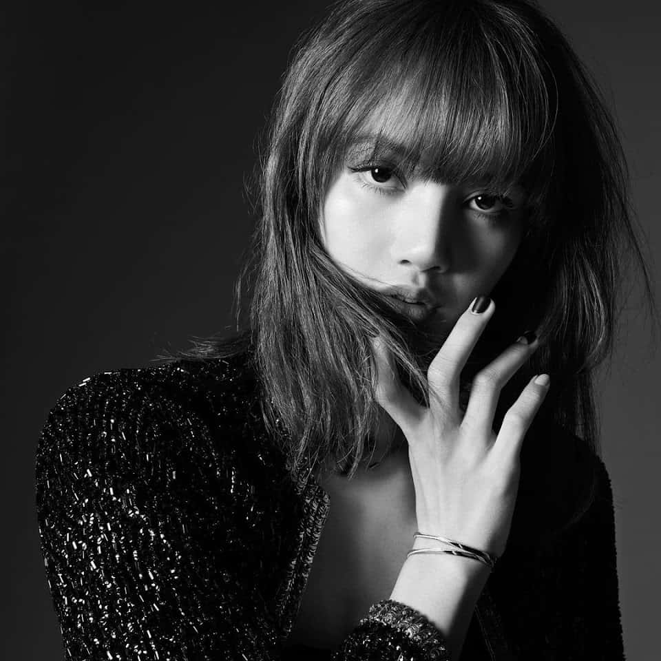 lisa 桌布 壁紙 — 一個黑白肖像，一位有瀏海和深色指甲油的女性在深色背景前觸摸她的臉。