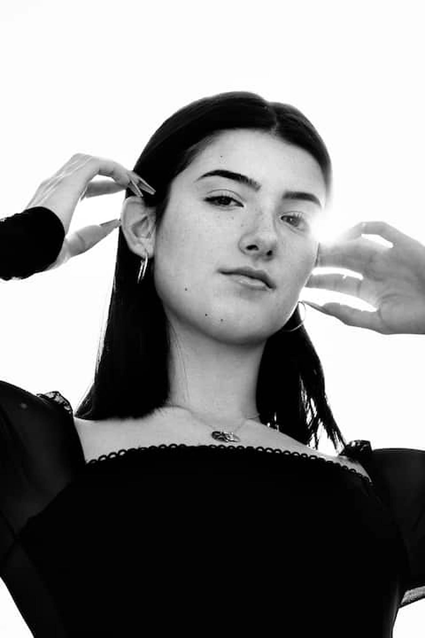 Charli D'amelio 桌布 壁紙 — 一個黑白肖像，一位深色頭髮和長指甲的女性，在明亮背景下框住她的臉。