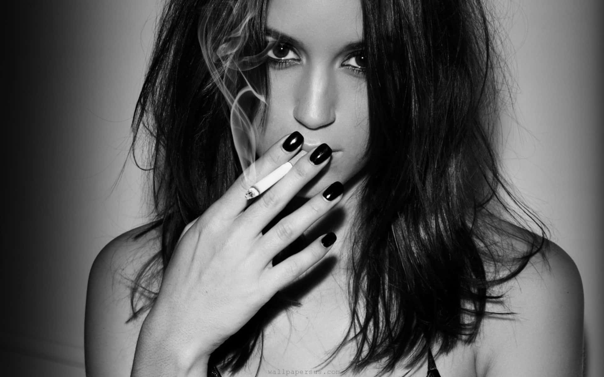 Girl Smoking 桌布 壁紙 — 一個黑白肖像，一位深色頭髮的女性將香煙靠近嘴唇，煙霧向上繚繞。