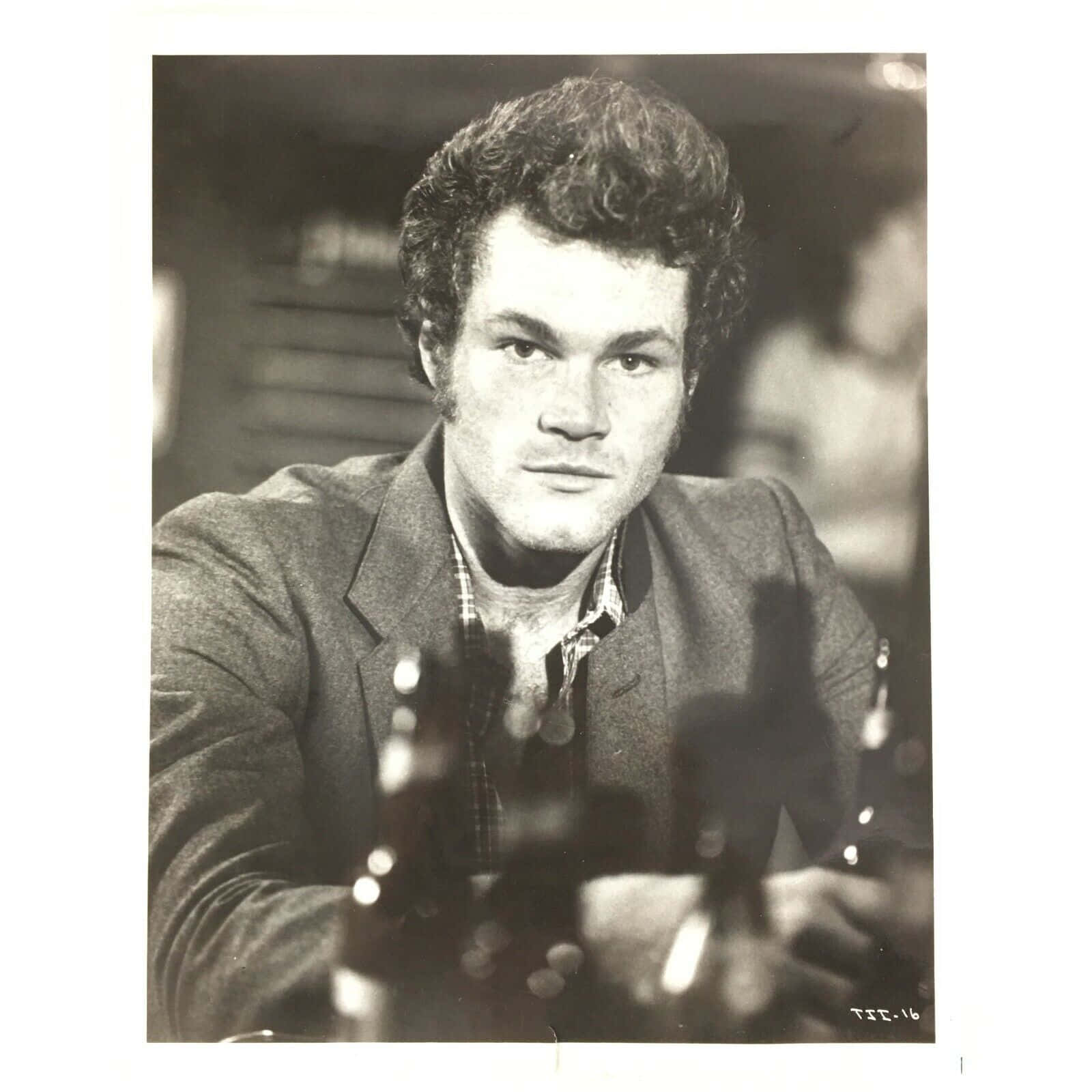 David Keith 桌布 壁紙 — 一個黑白肖像，一個捲髮男人坐在酒吧前，面前有酒瓶，專注地看著相機。