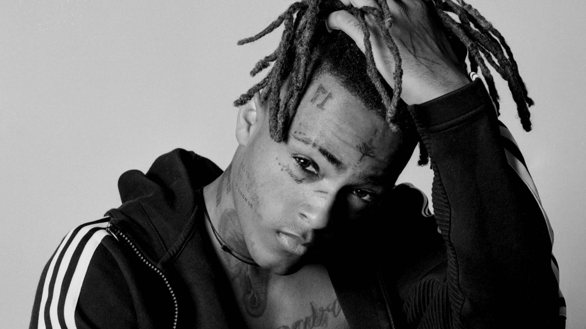 xxxtentacion 電腦 桌布 壁紙 — 一個黑白肖像，一個有刺青、梳著辮子頭的男人，頭靠著純色背景。
