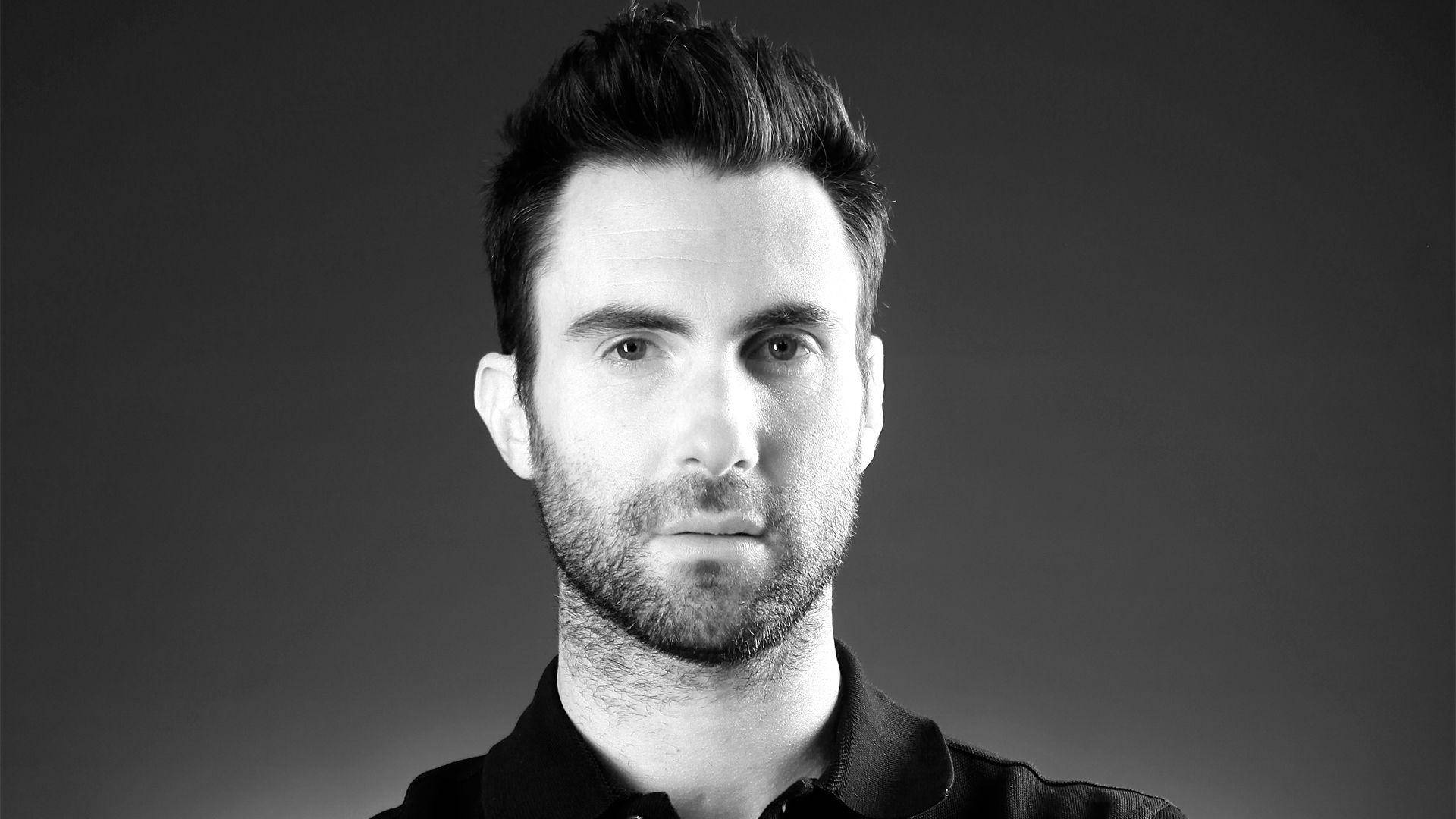 Adam Levine 桌布 壁紙 — 一個黑白肖像，一個有造型頭髮和鬍渣的男人，在漸變灰色背景前直視鏡頭。