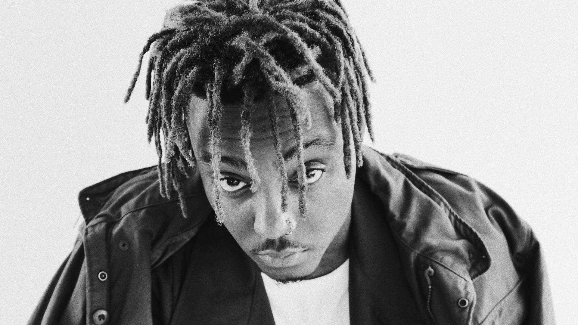 一個留著辮子、戴著鼻環的男人在黑白工作室肖像中直視相機。 — Juice Wrld 壁紙