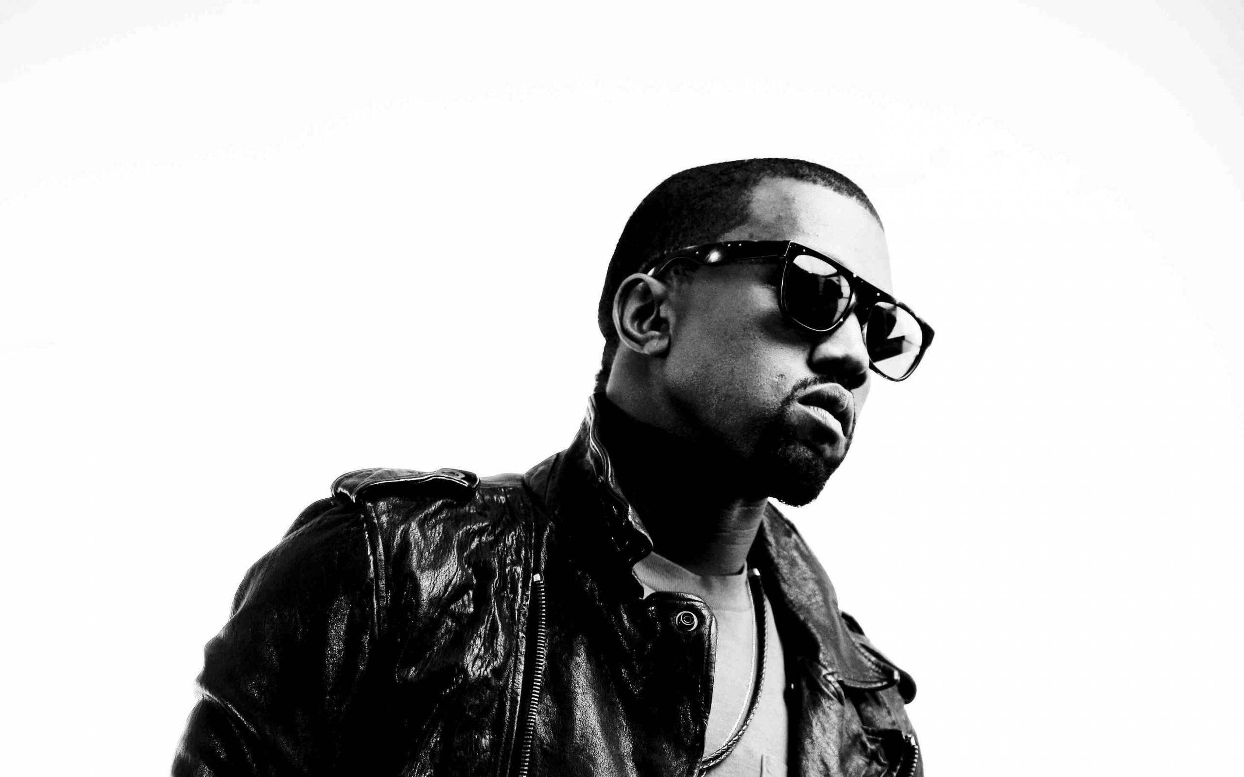 Kanye 桌布 壁紙 — 一個黑白肖像，一個穿著皮夾克和太陽眼鏡的男人，背景是純白色。