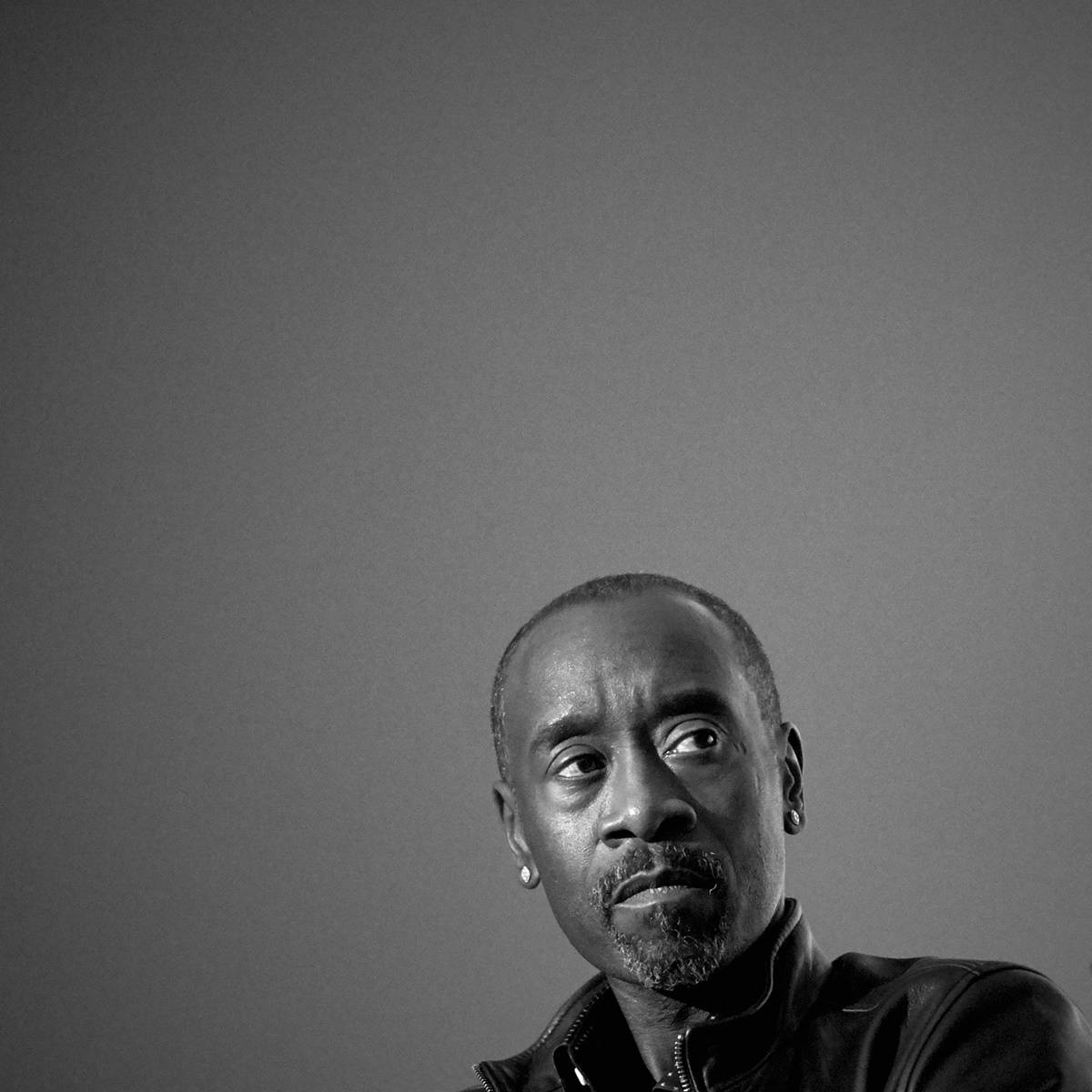 Don Cheadle 桌布 壁紙 — 一個黑白肖像，一個表情嚴肅的男人在純灰色背景上向上看。