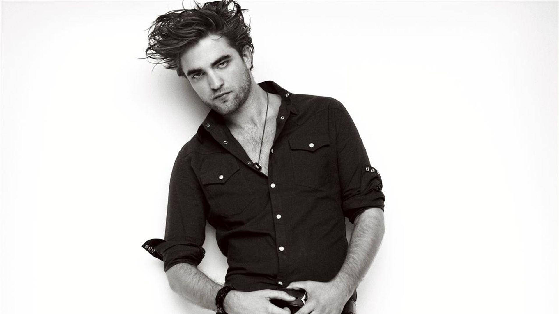 Robert Pattinson 桌布 壁紙 — 一個黑白肖像，一個頭髮蓬亂的男人靠著素牆，穿著深色鈕扣襯衫。