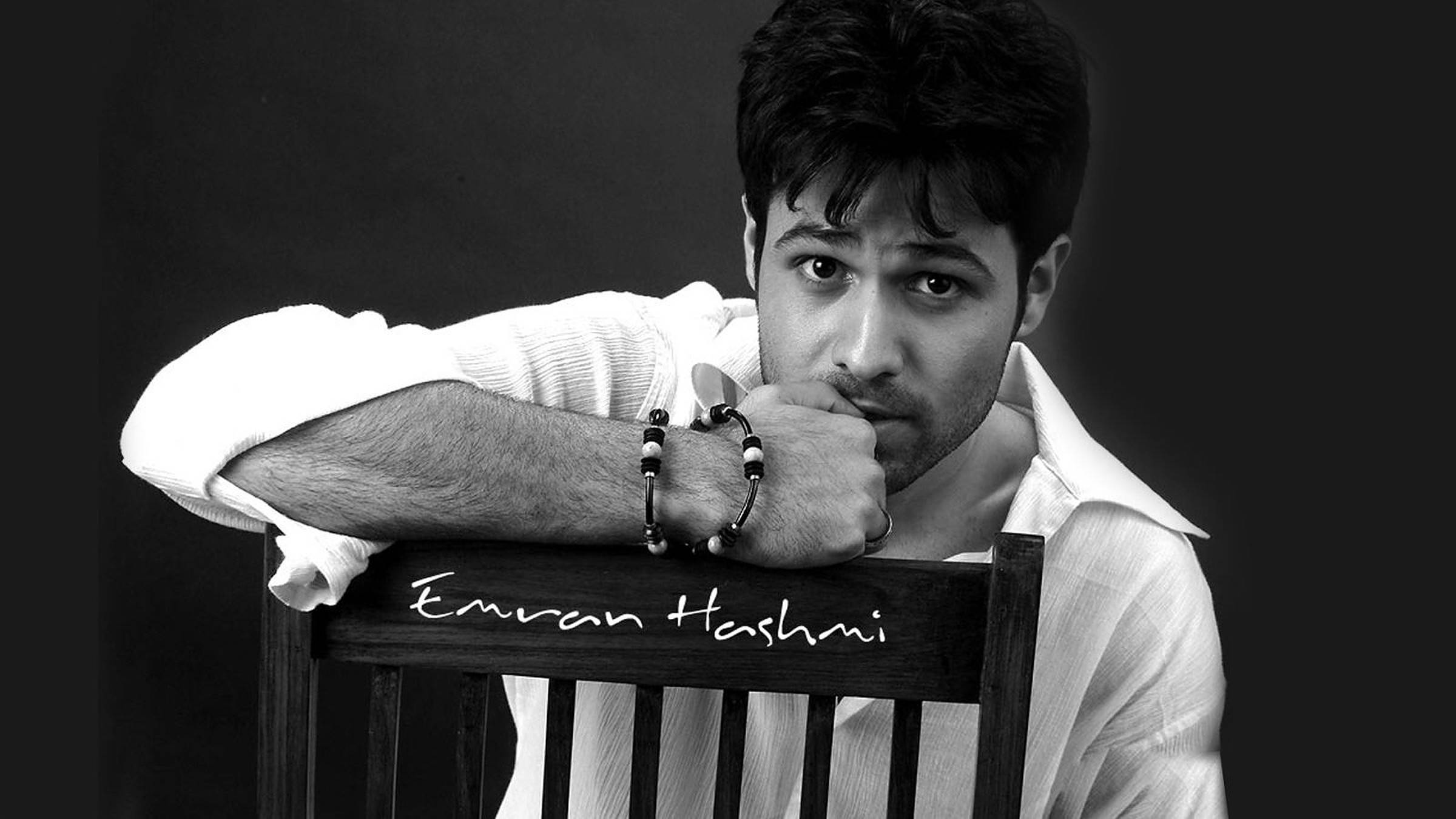Emraan Hashmi 桌布 壁紙 — 一個黑白肖像，一名男子靠在椅子上，椅背上寫有他的名字。