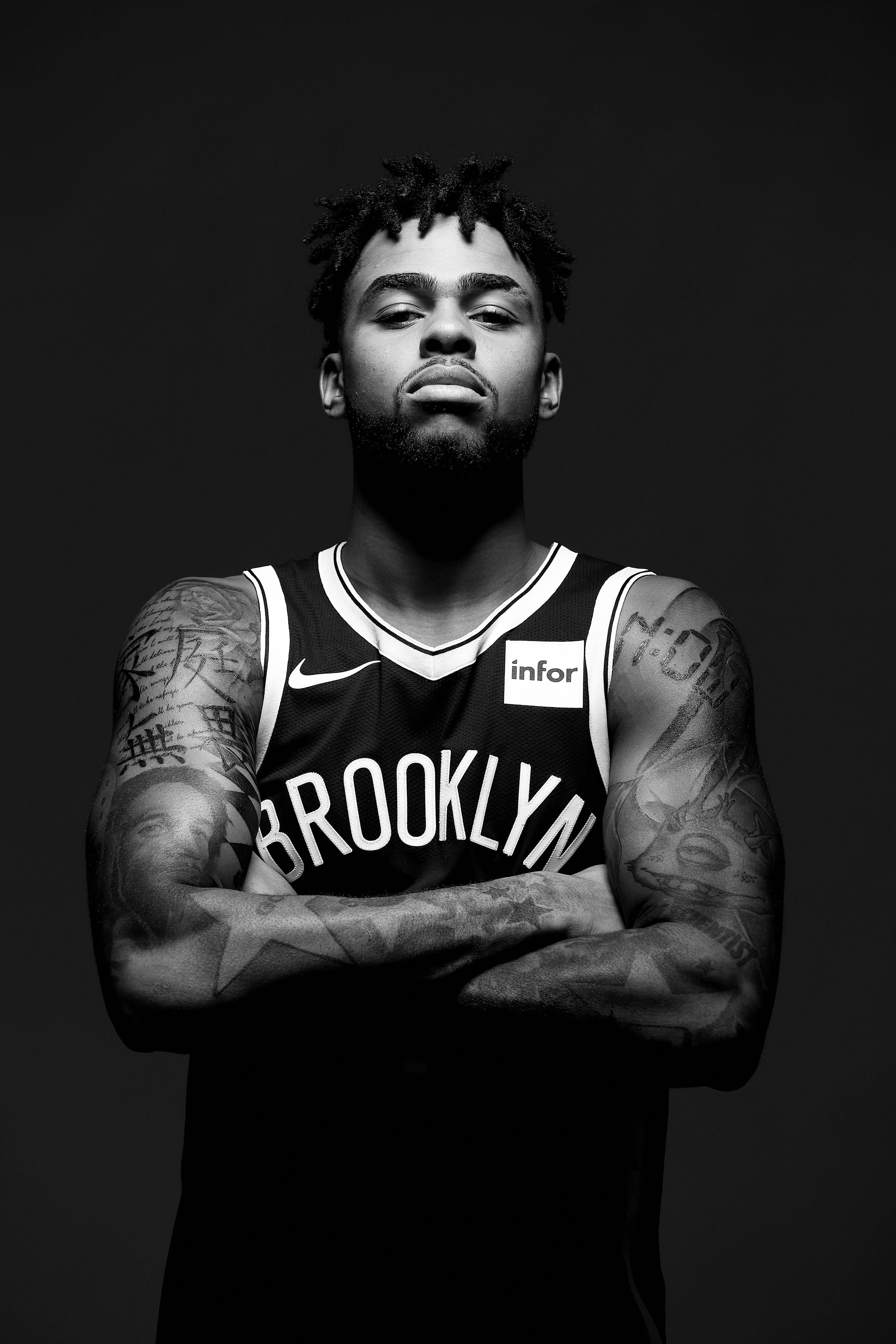 NBA 桌布 壁紙 — 一個黑白肖像，一名紋身籃球運動員身穿布魯克林球衣，雙臂交叉站在深色背景前。