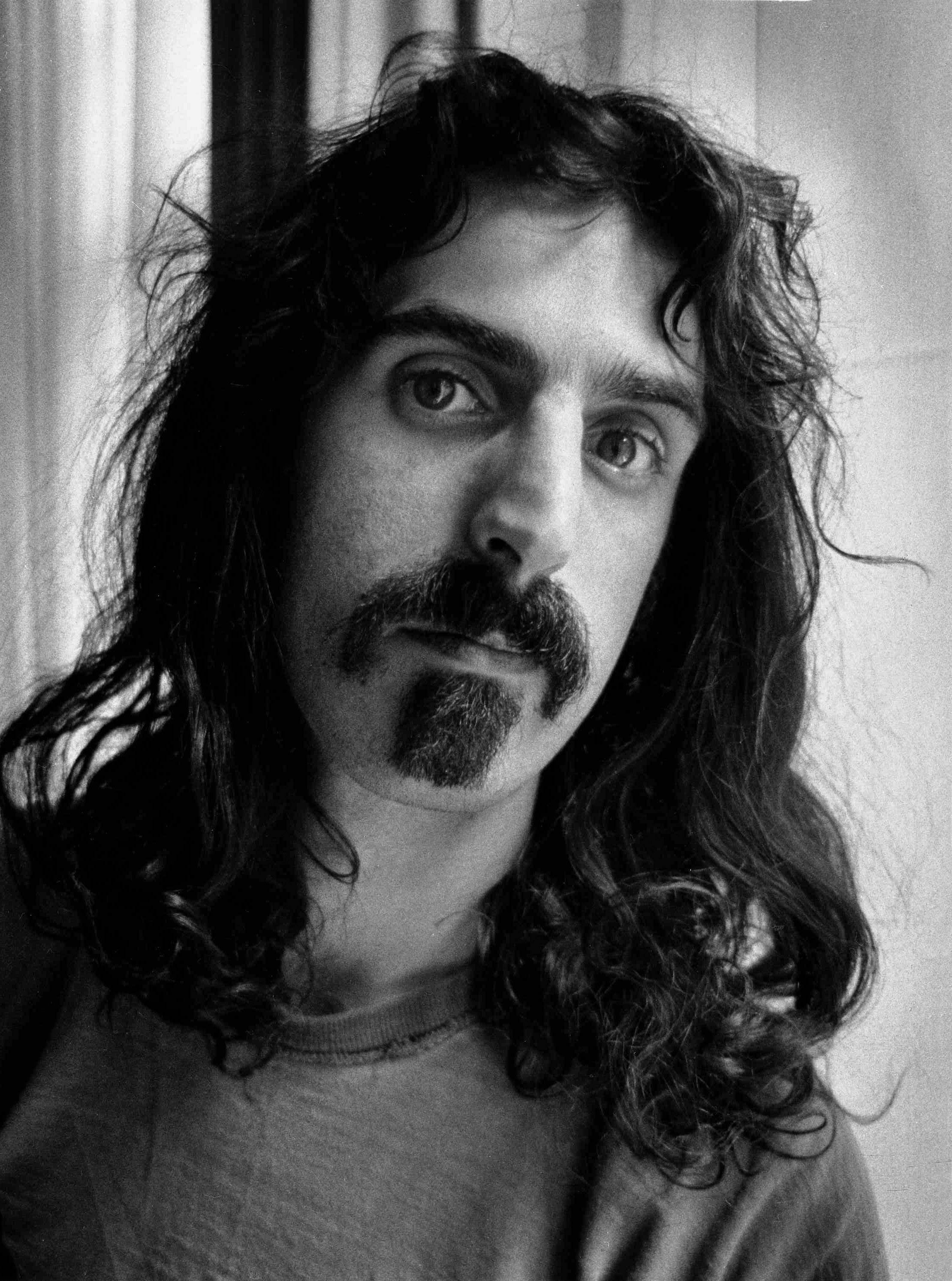Zappa 桌布 壁紙 — 一個黑白肖像，拍攝一位留著長波浪髮和山羊鬍的男人，專注地凝視著相機。