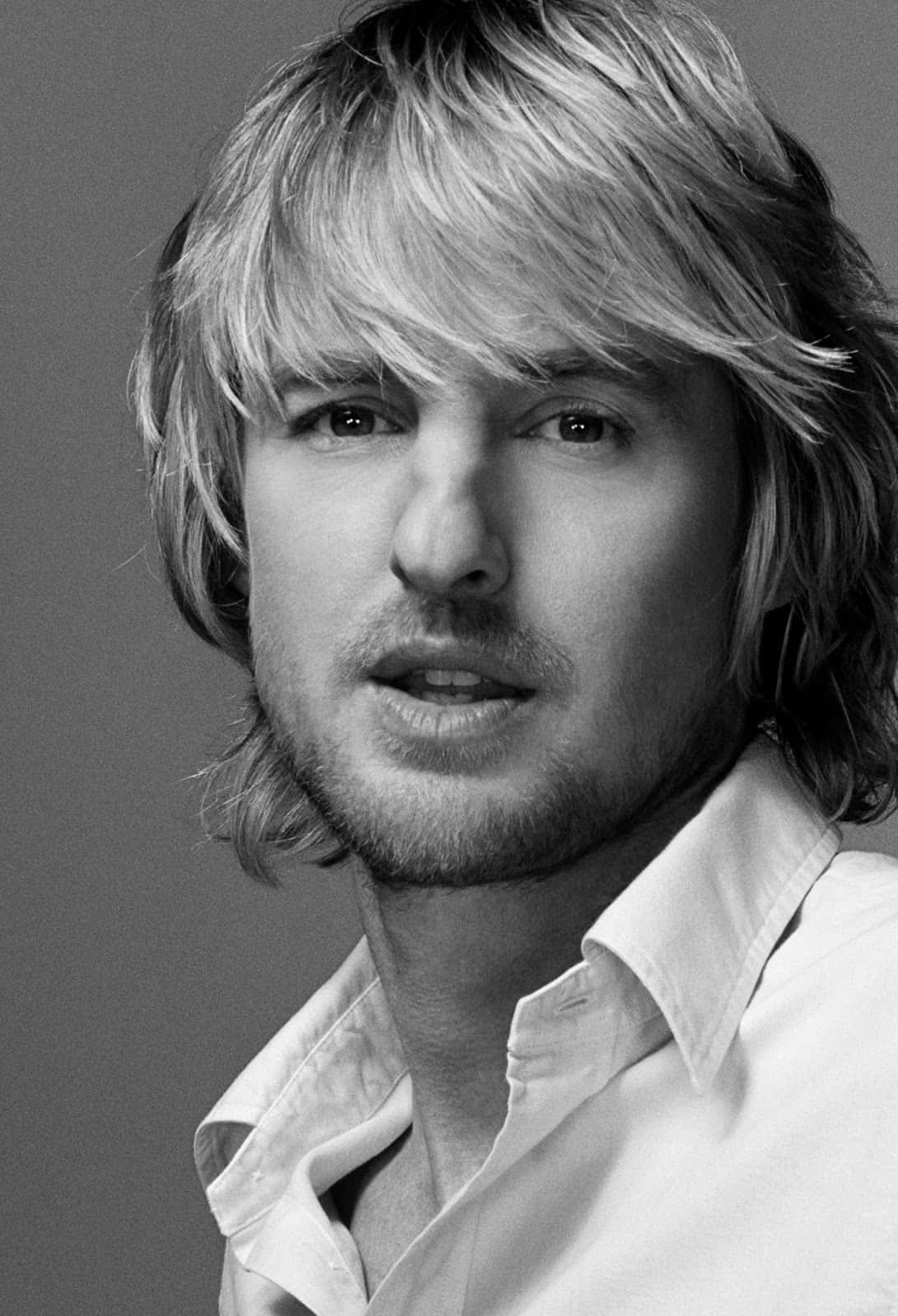 Owen Wilson 桌布 壁紙 — 一個黑白肖像，拍攝一位頭髮蓬鬆金髮、帶有輕微鬍渣的男人，直視鏡頭。