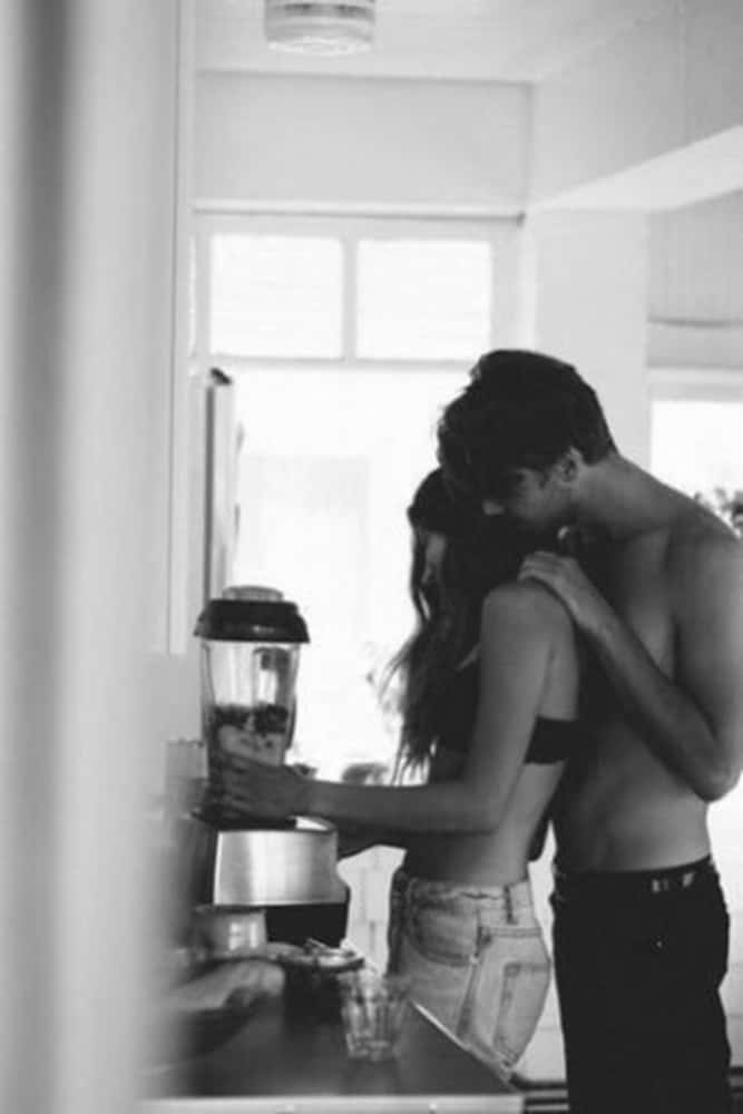 Girlfriend And Boyfriend 桌布 壁紙 — 一個黑白親密時刻，一個赤裸上身的男人從後面擁抱一個正在廚房攪拌飲品的女人。