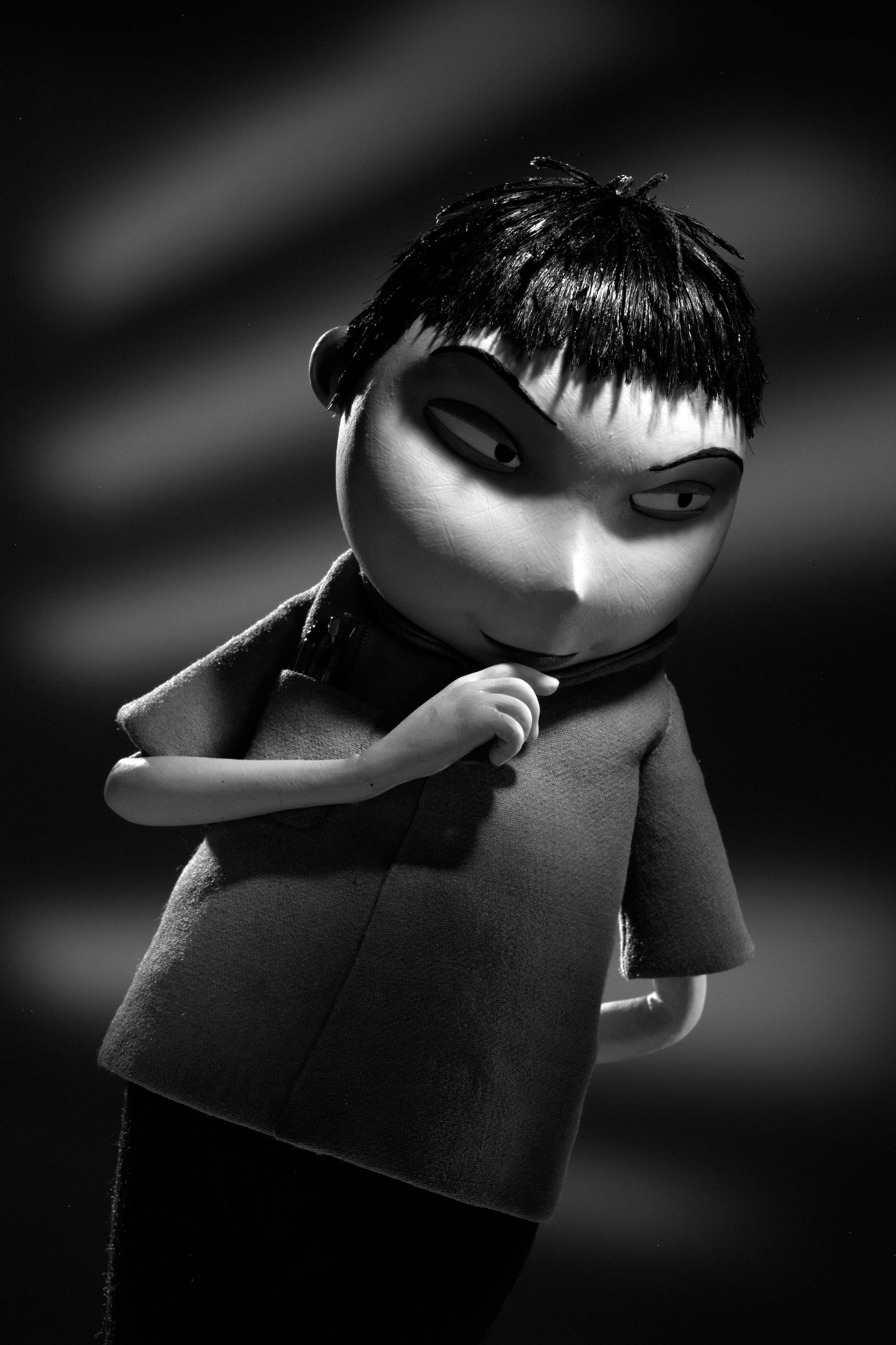 Frankenweenie 桌布 壁紙 — 一個黑白風格化的動畫角色，眼神銳利，帶著得意的笑容，在模糊的條紋背景前擺姿勢。