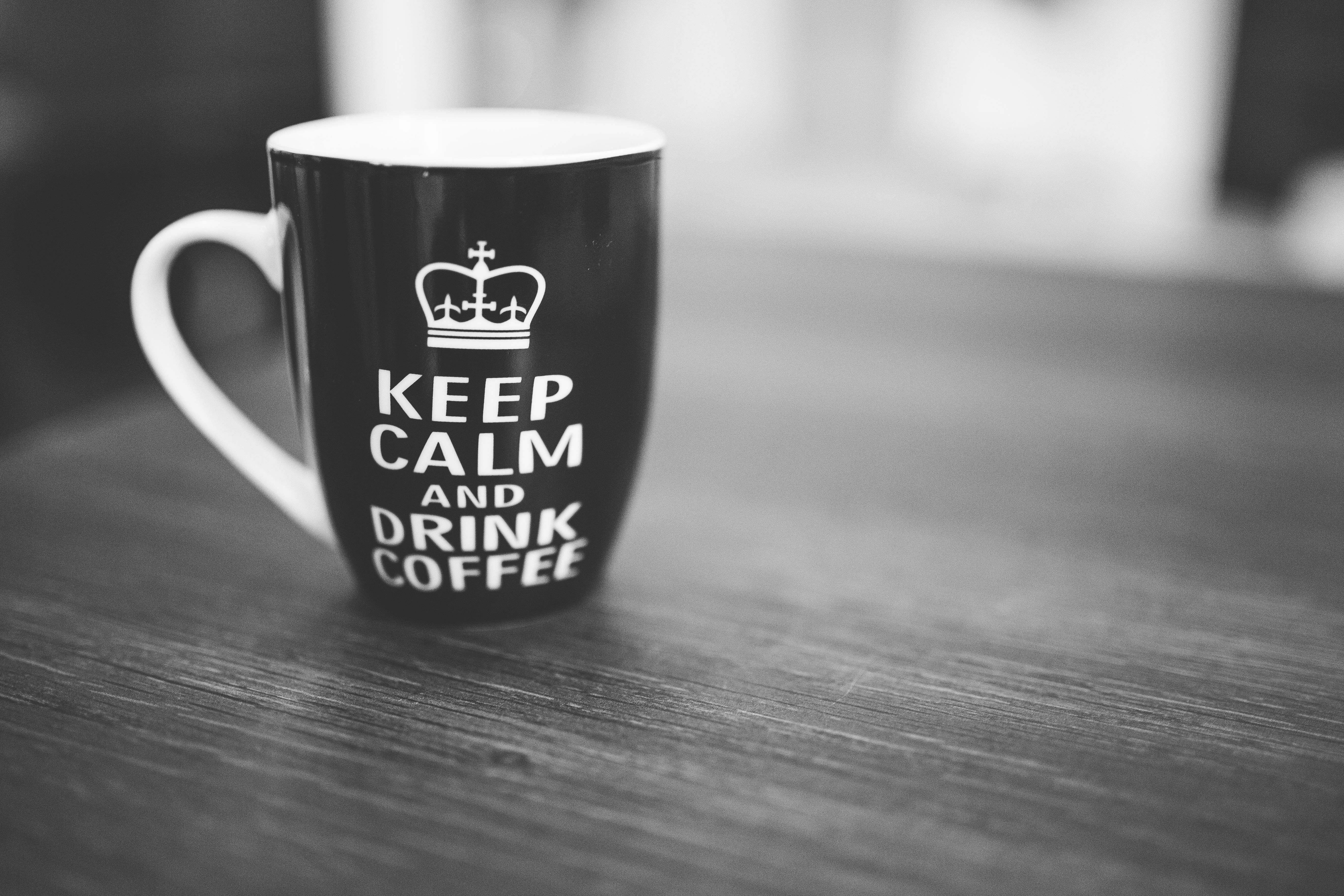keep 桌布 壁紙 — 一個黑白馬克杯，上面有皇冠和「KEEP CALM AND DRINK COFFEE」字樣，放在木桌上。