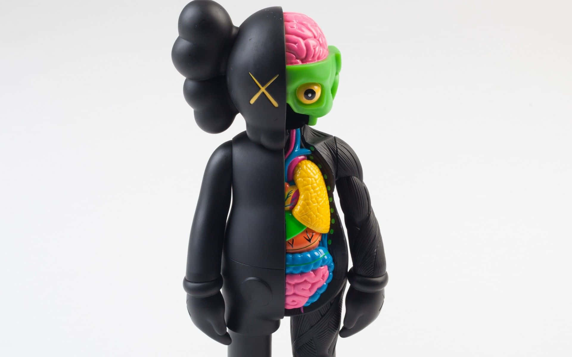 KAWS 桌布 壁紙 — 一個黑色KAWS公仔被剖開，露出色彩繽紛的內臟和粉紅色大腦，背景為白色。