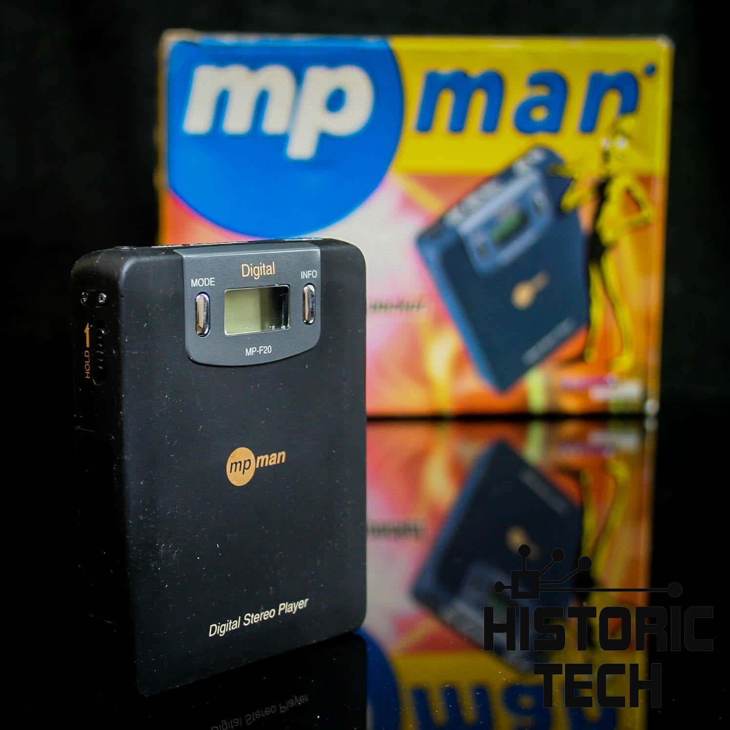 Music Player 桌布 壁紙 — 一個黑色mp man數位立體聲播放器放在其彩色盒子前面，置於反光表面上。