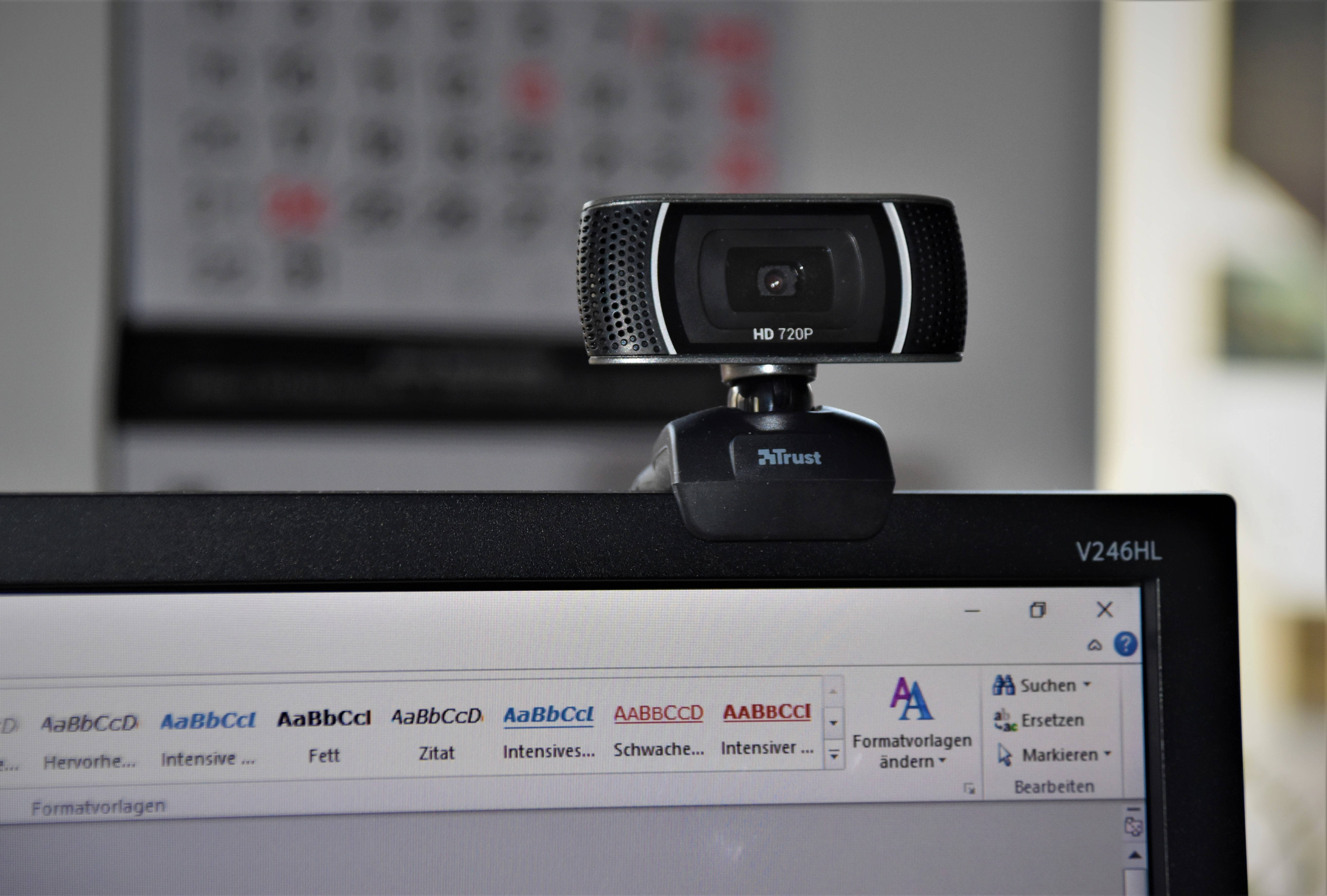 Webcam 桌布 壁紙 — 一個黑色Trust HD 720p網路攝影機放置在顯示德國文字處理器介面的電腦顯示器上。