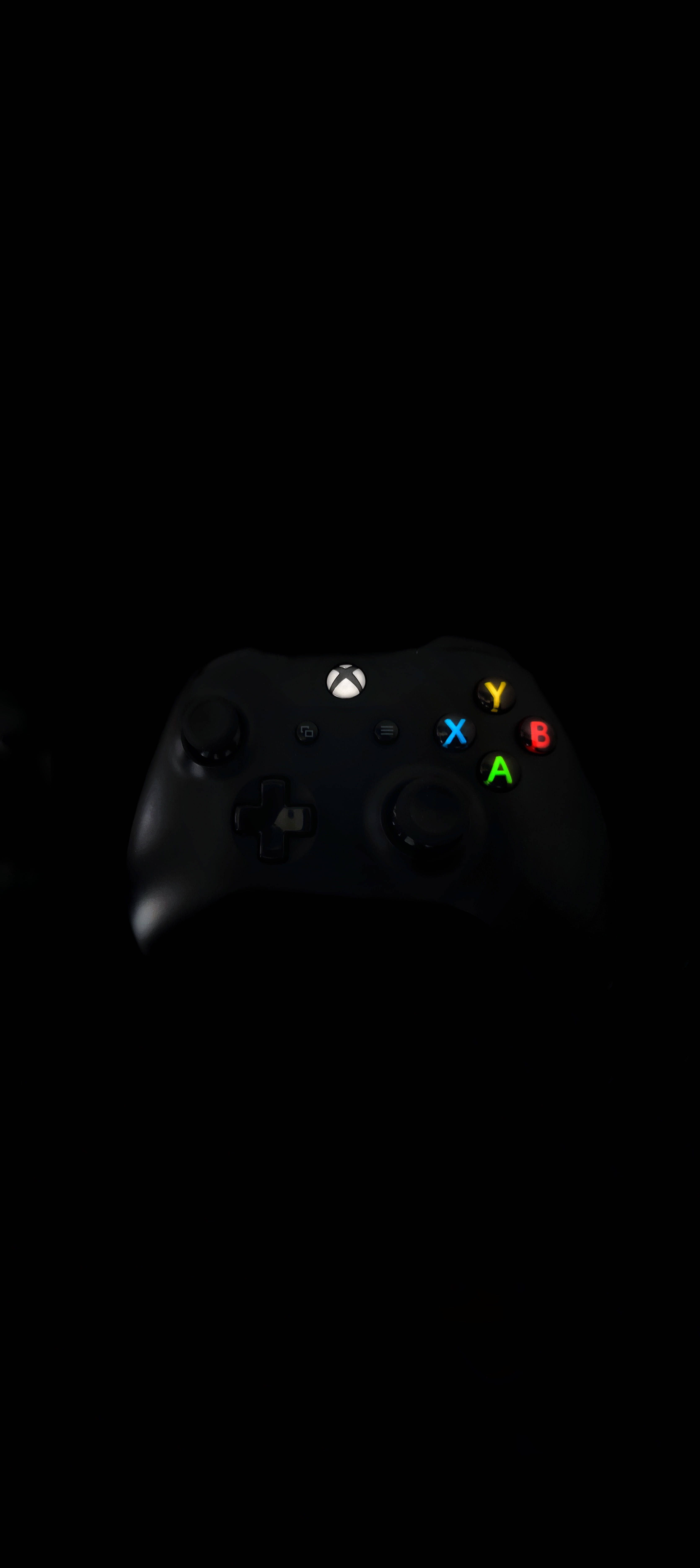 Xbox 桌布 壁紙 — 一個黑色Xbox控制器在漆黑背景上發出彩色按鈕的光芒。