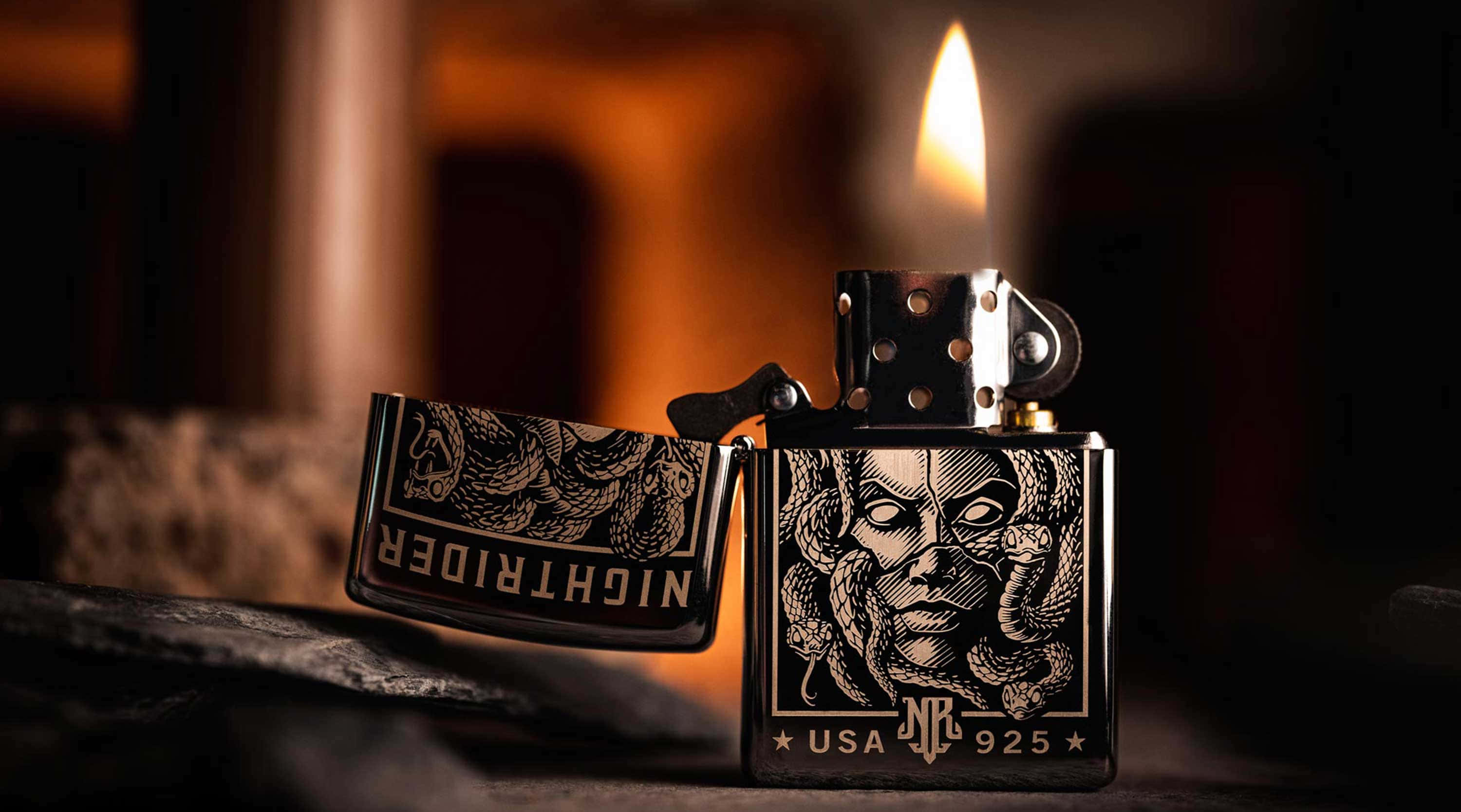 lighter 桌布 壁紙 — 一個黑色Zippo打火機，帶有詳細的蛇面設計，在柔和模糊的暖色背景前閃爍著溫暖的火焰。