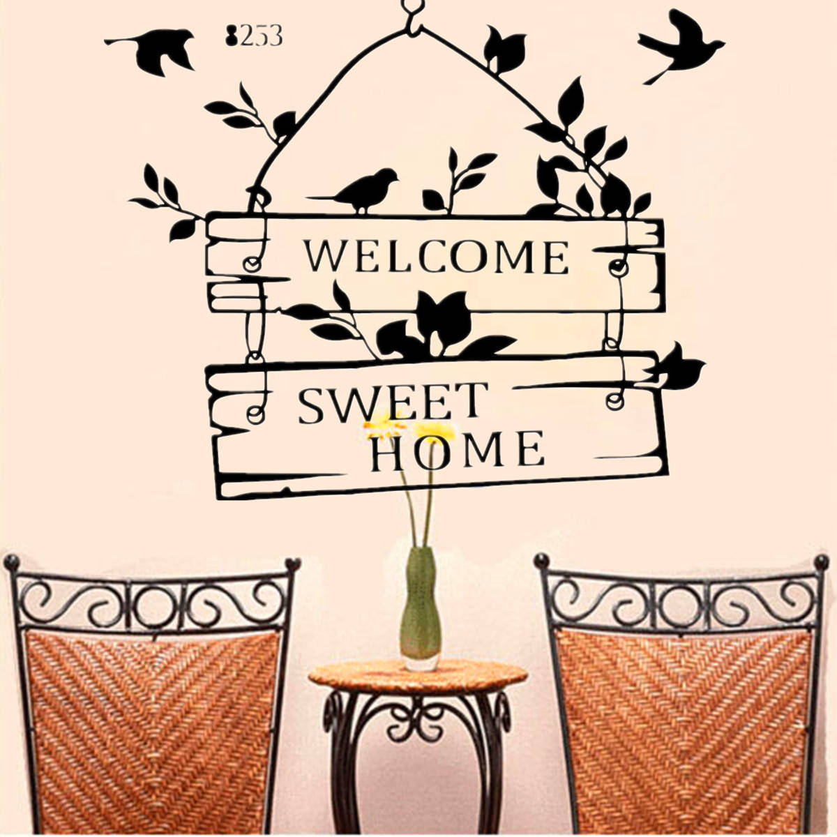 Home Sweet Home 桌布 壁紙 — 一個黑色剪影牆貼，圖案為懸掛的「WELCOME SWEET HOME」標誌，上有鳥和葉子，下方有兩張柳條椅和一張放有黃色小花的小桌子。