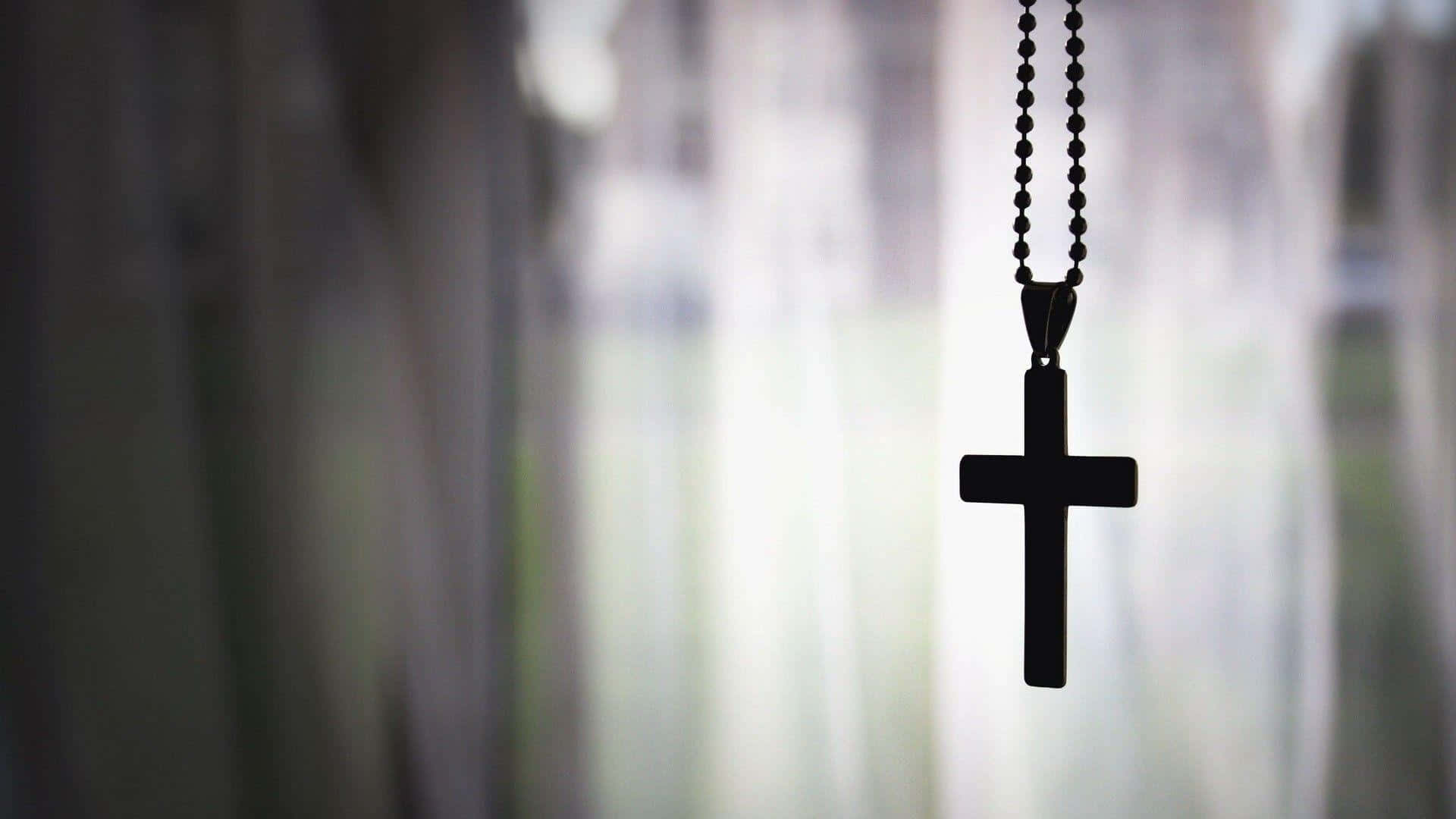 Catholic Desktop 桌布 壁紙 — 一個黑色十字架吊墜在柔和模糊的窗戶和漫射日光下以剪影懸掛。