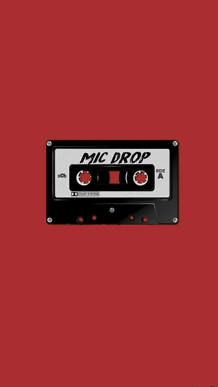 紅色美學動圖 桌布 壁紙 — 一個黑色卡式錄音帶，標有「MIC DROP」，置中於純紅色背景上。