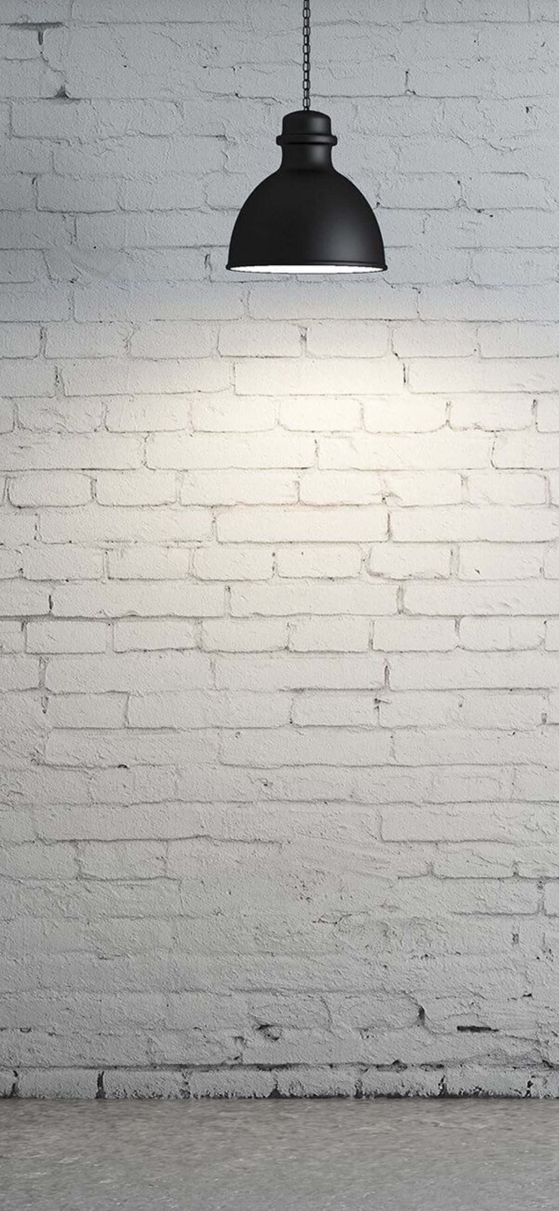 Brick Wall 桌布 壁紙 — 一個黑色吊燈掛在帶有紋理的白色磚牆上，在混凝土地板上投射出柔和的光芒。
