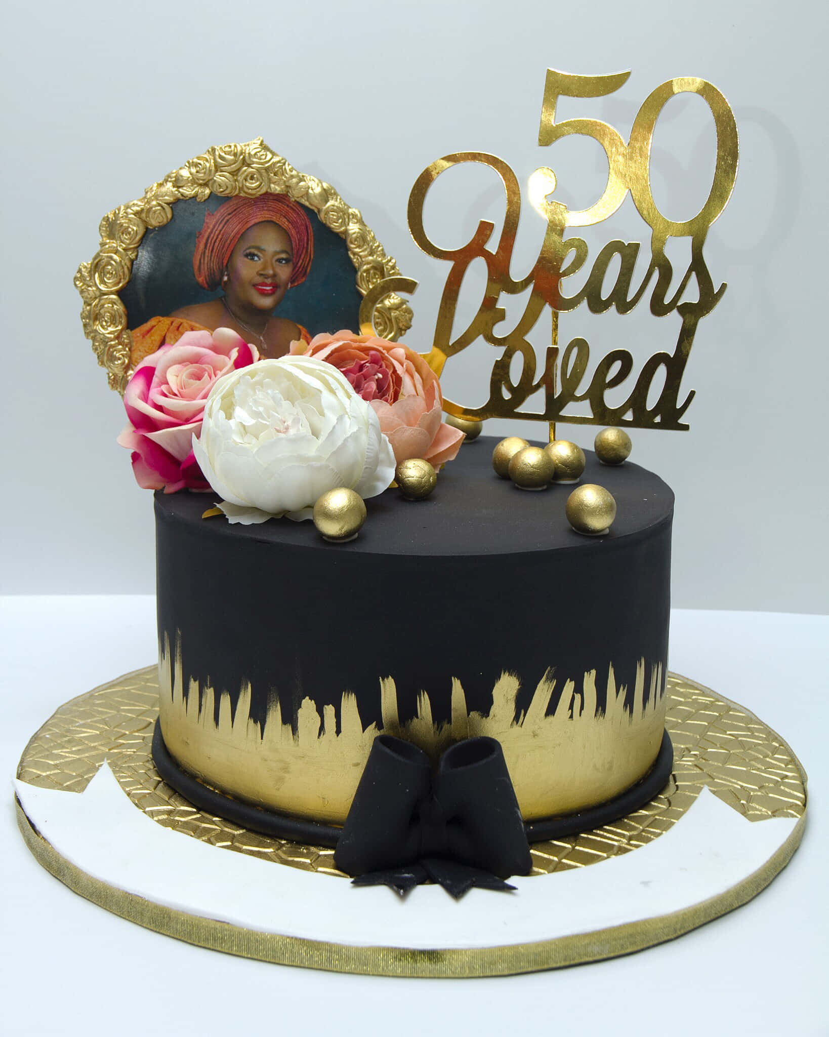 Cake Fondant 桌布 壁紙 — 一個黑色和金色的慶祝蛋糕，上面有玫瑰、肖像和一個50 Years Loved的蛋糕裝飾。