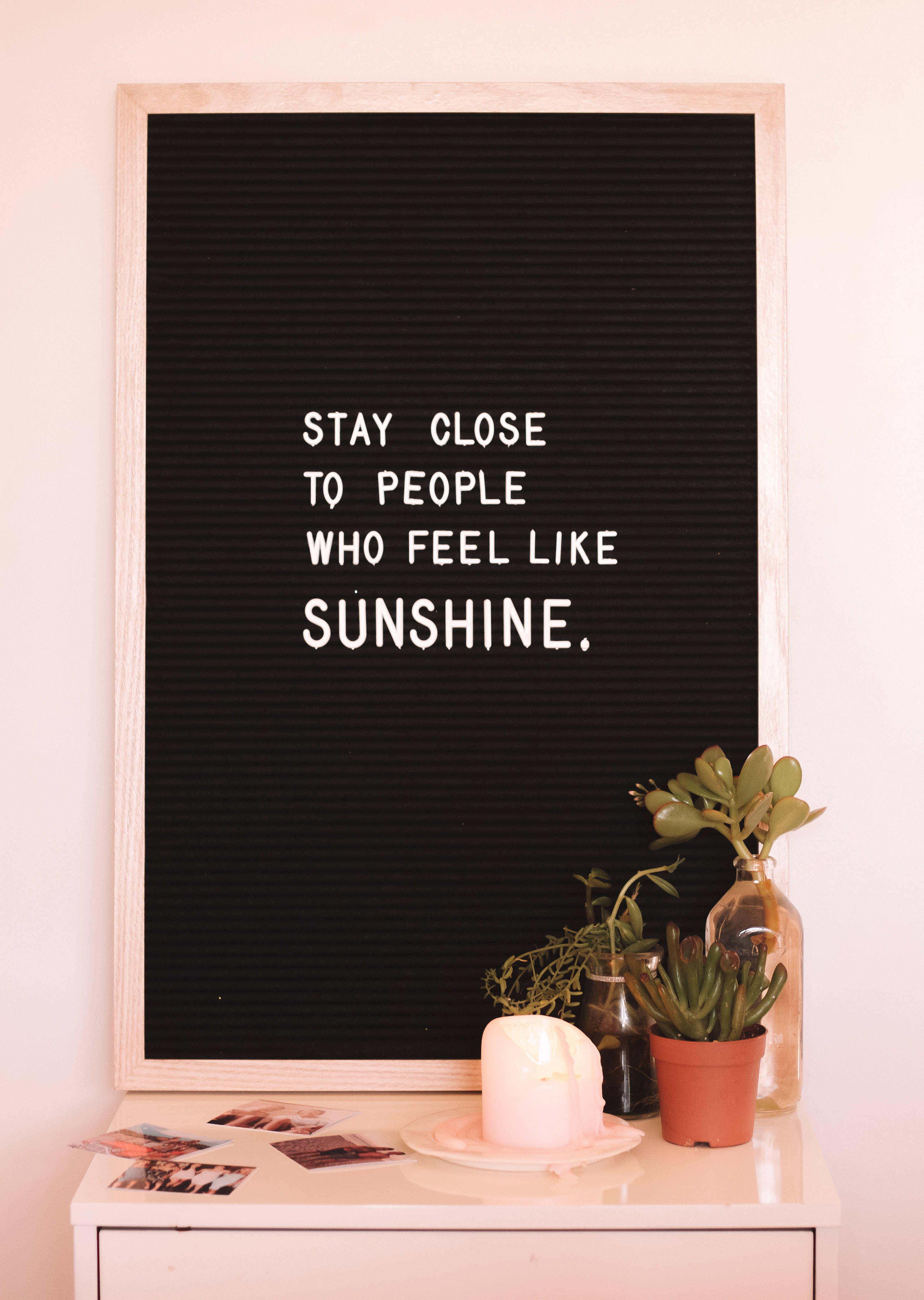 Quote 桌布 壁紙 — 一個黑色字母板，上面有白色文字寫著 'STAY CLOSE TO PEOPLE WHO FEEL LIKE SUNSHINE'，放在白色架子上，旁邊有盆栽多肉植物和蠟燭。