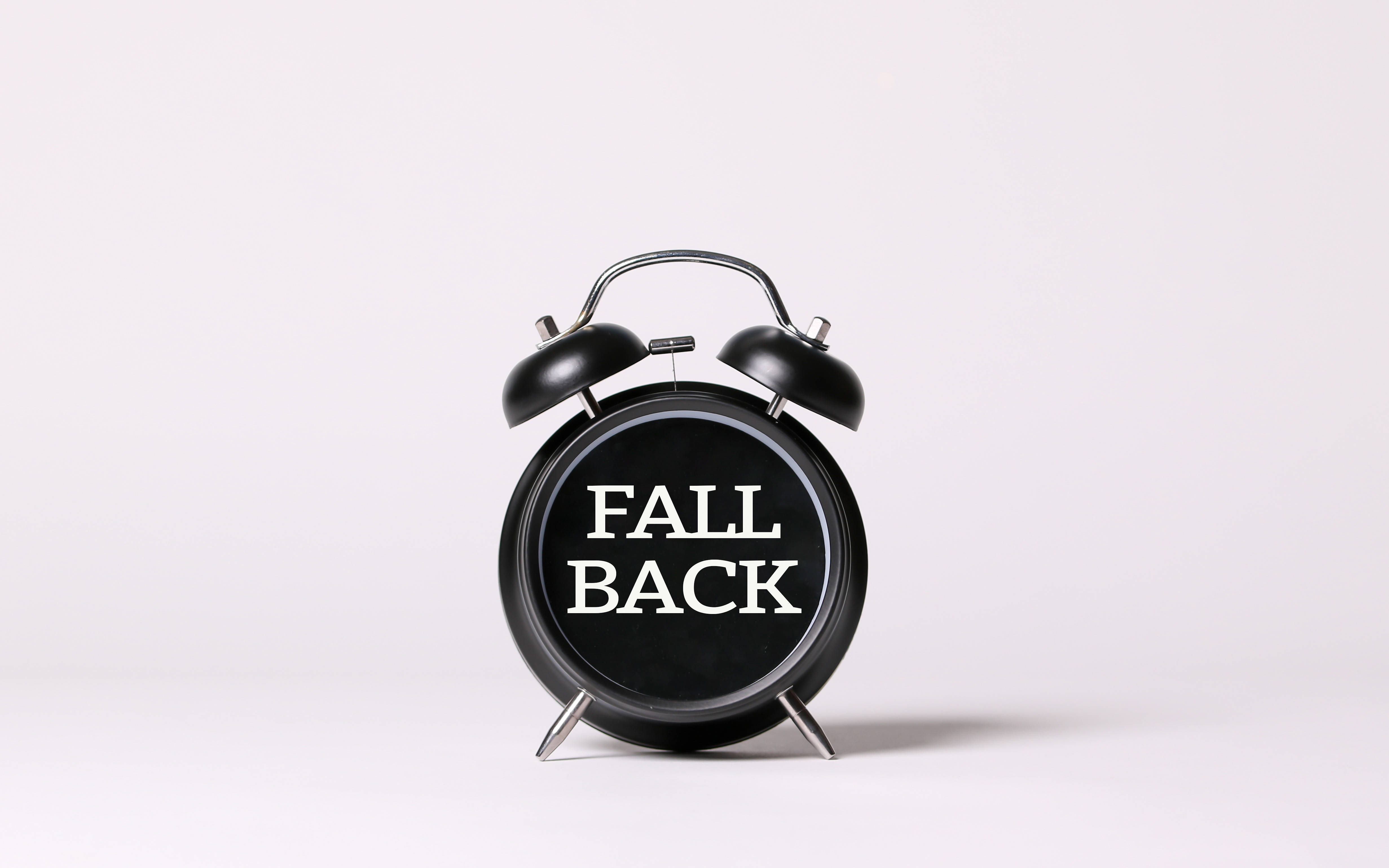 時鐘 桌布 壁紙 — 一個黑色復古鬧鐘，上面有「FALL BACK」字樣，置於純白色背景中央。