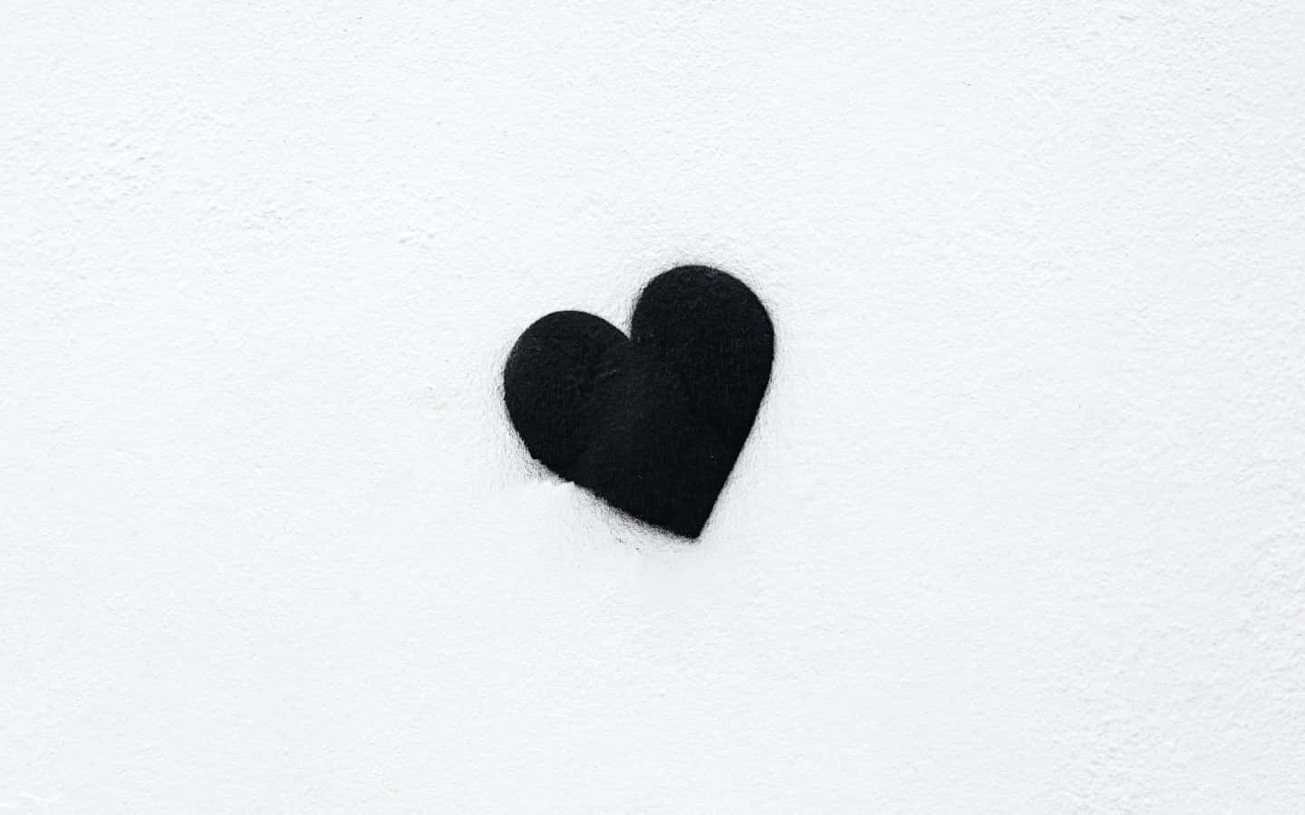 Black And White Heart 桌布 壁紙 — 一個黑色心形圖案畫在有紋理的白色牆上，帶有柔和陰影。