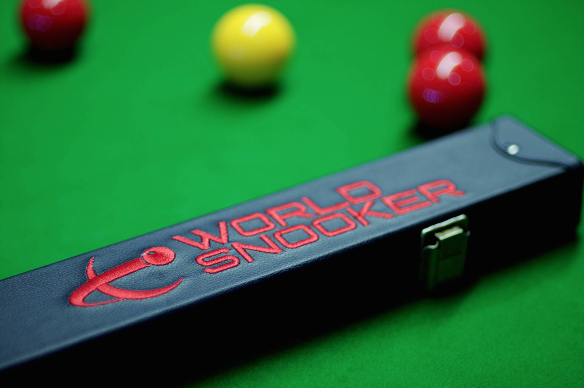 Snooker 桌布 壁紙 — 一個黑色撞球桿套的特寫，上面有紅色 'WORLD SNOOKER' 標誌，放在一張鮮綠色絨面撞球桌上，周圍散落著球。