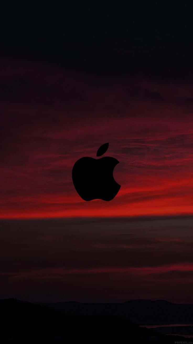 桌布 壁紙 — 一個黑色的Apple標誌剪影在遠處山丘上熾熱的紅色和深紫色日落天空中脫穎而出。