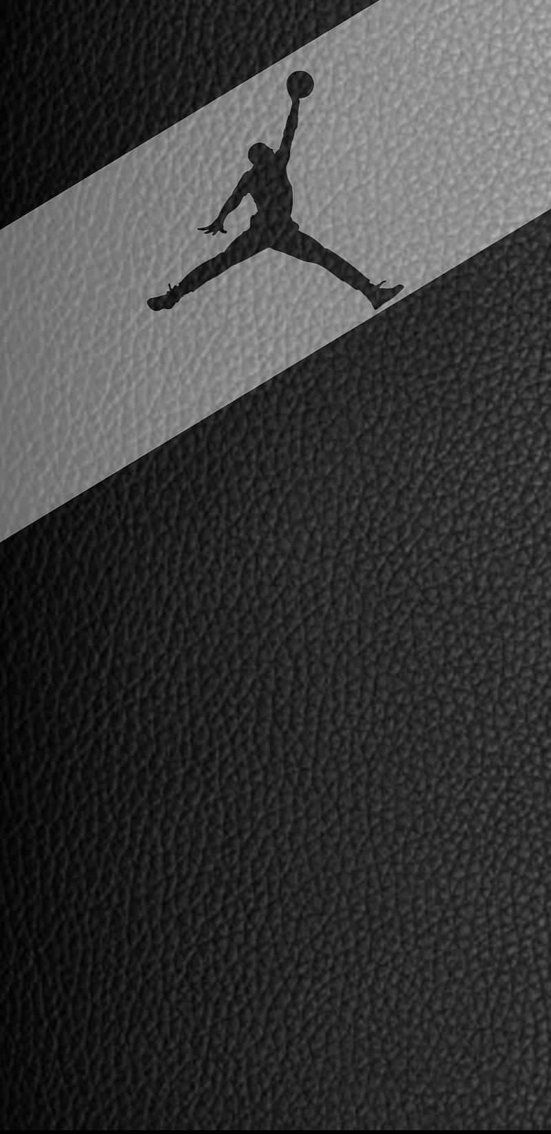 Jordan Logo Phone 桌布 壁紙 — 一個黑色的Jordan標誌剪影，在帶有紋理的黑色皮革背景上，動態地跳過一條對角灰色條紋。