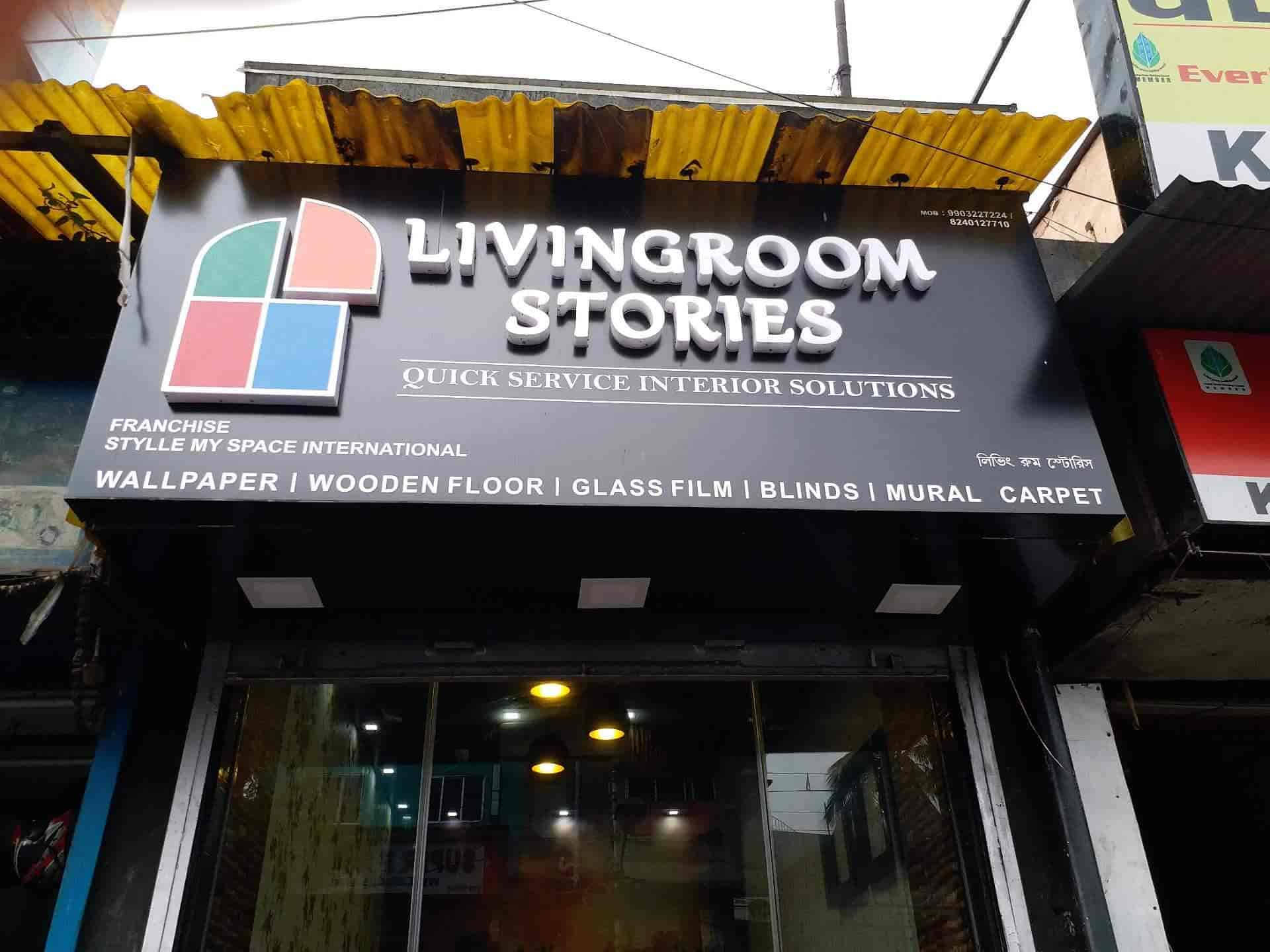 Kolkata 桌布 壁紙 — 一個黑色的店面招牌，上面寫著「Livingroom Stories」，有色彩繽紛的幾何標誌和白色文字，在黃色波浪形雨棚下宣傳室內設計方案。
