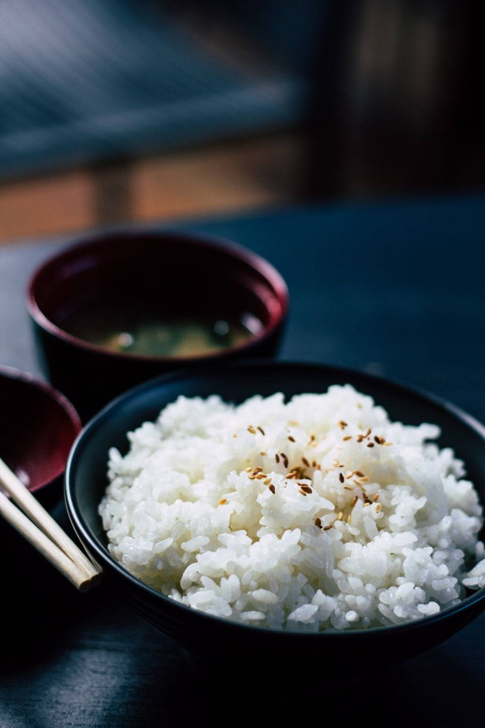 烹飪 桌布 壁紙 — 一個黑色碗中盛載的蒸白米飯近距離特寫，上面撒有烤芝麻，旁邊放著一個紅色漆器杯的味噌湯。