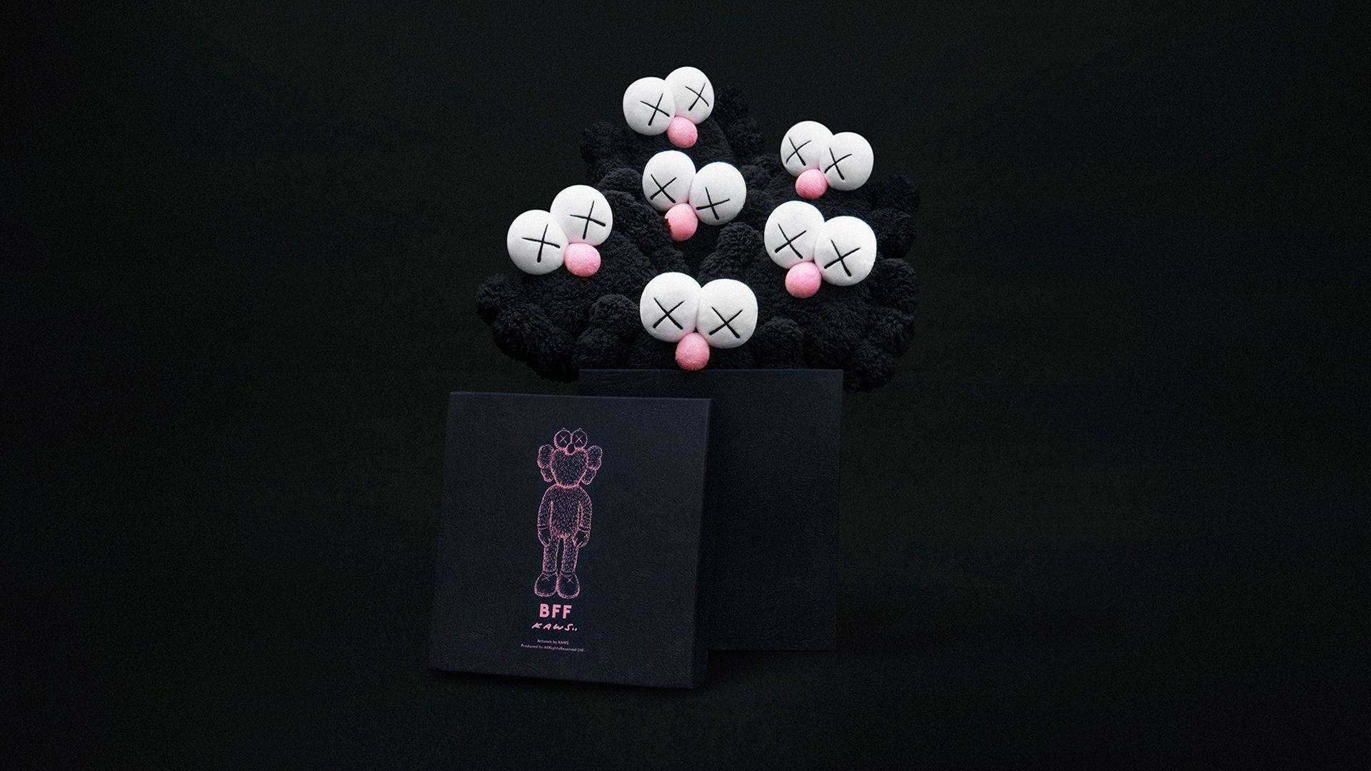 KAWS 桌布 壁紙 — 一個黑色紋理雕塑，頂部有白色球體，帶有X形眼睛和粉紅色鼻子，旁邊有一個黑色盒子，上面有粉紅色輪廓的熊插圖。