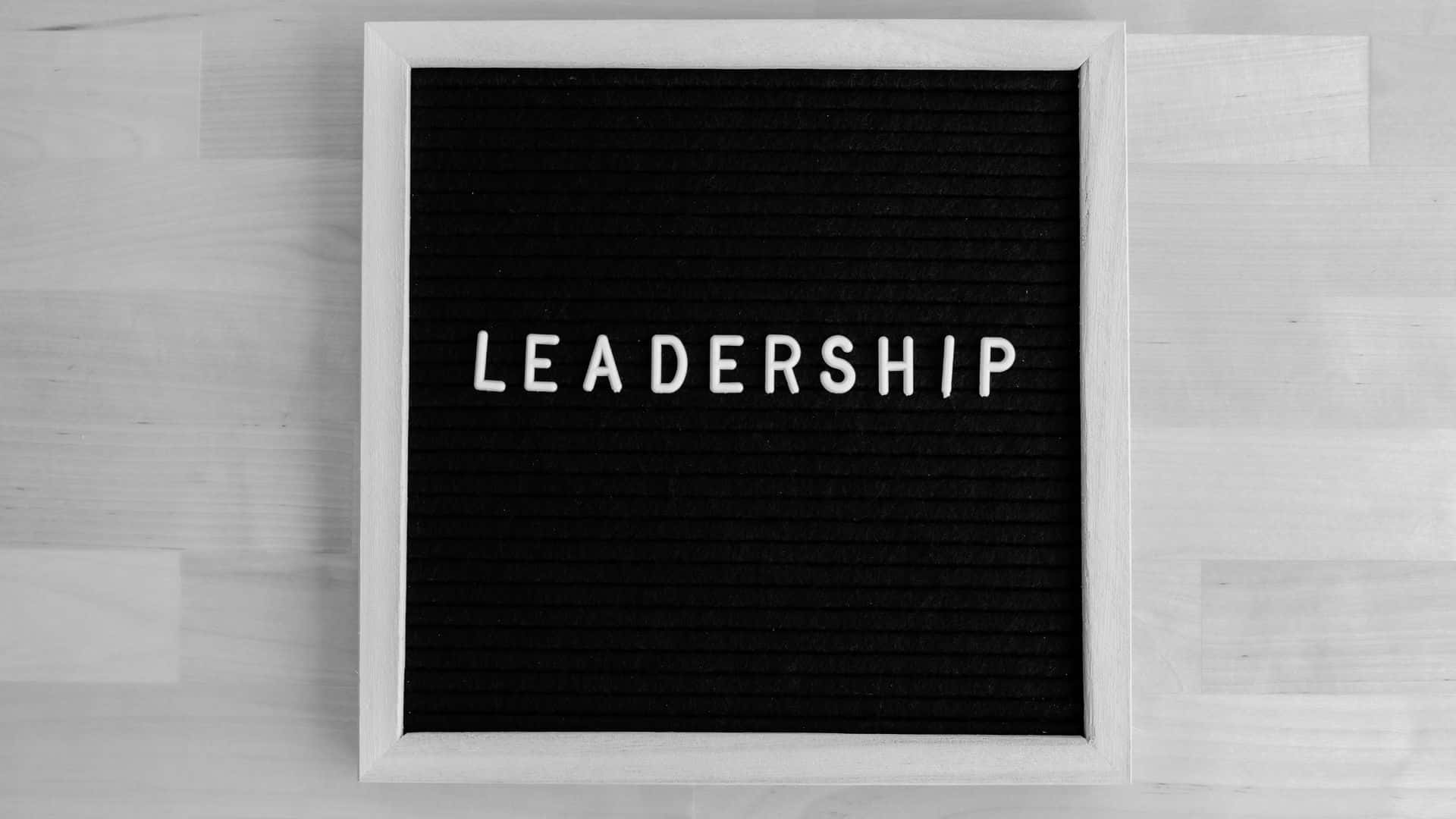 Black And White Word 桌布 壁紙 — 一個黑色絨毛字母板，上面用白色字母拼出 leadership，放在淺色木質表面的中央。