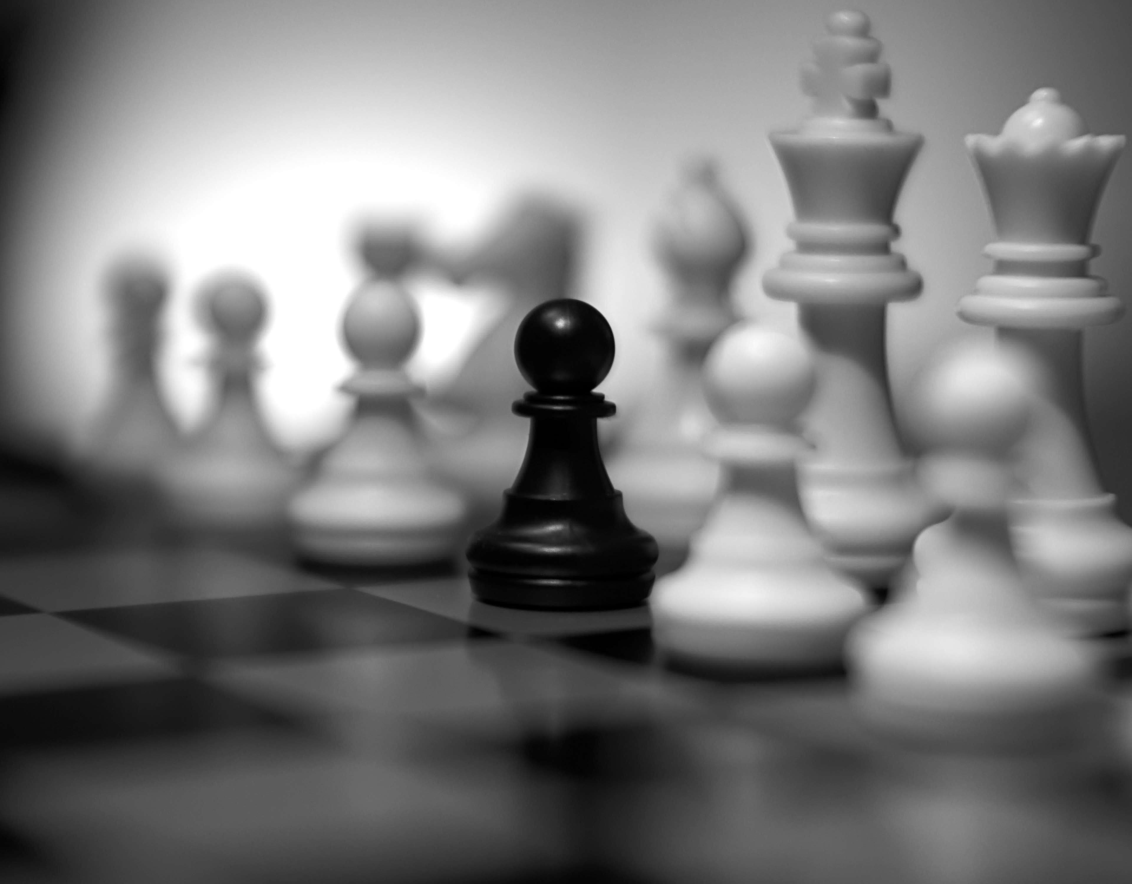Black And White Chess 桌布 壁紙 — 一個黑色西洋棋兵在棋盤上清晰對焦，周圍是模糊的白色棋子，呈單色。
