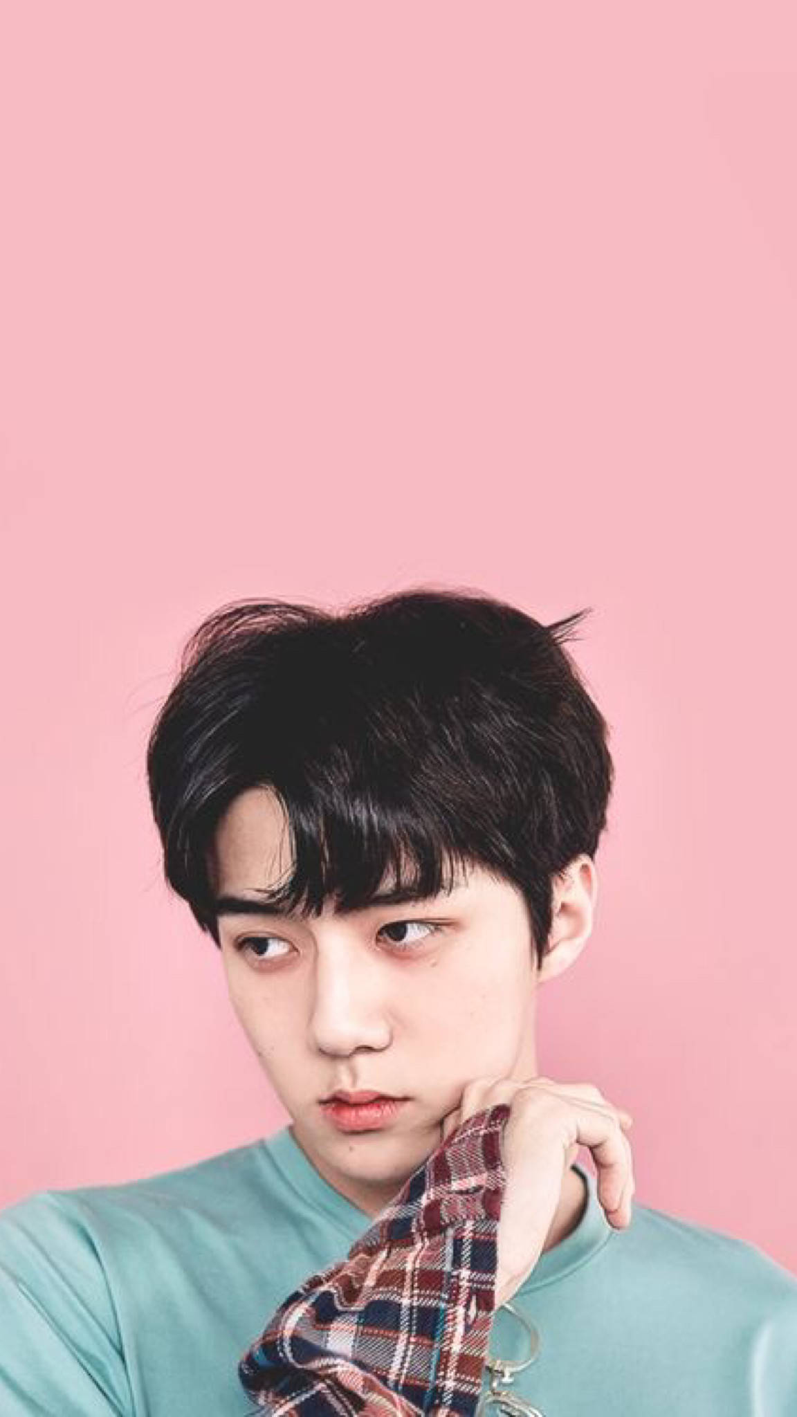 EXO 桌布 壁紙 — 一個黑髮、表情深思的年輕男子，在柔和的粉紅色背景上，將下巴擱在格紋襯衫上。