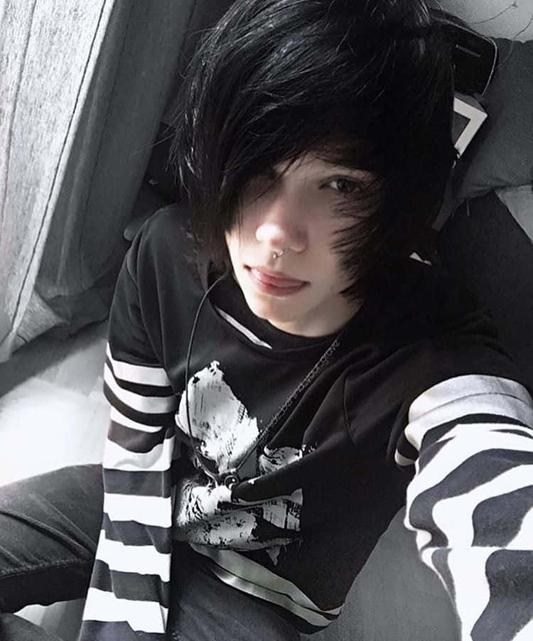 emo 美學 桌布 壁紙 — 一個黑髮戴鼻環的人躺在床上放鬆，穿著黑白條紋襯衫。