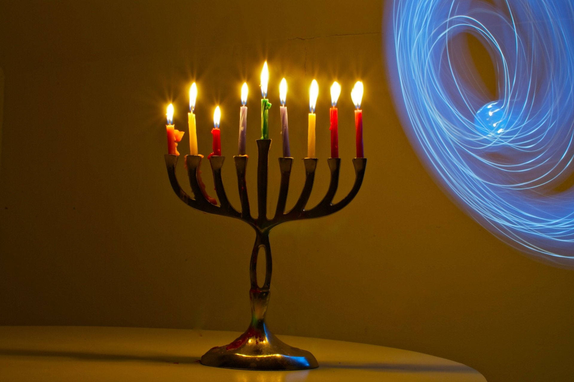帶有燃燒蠟燭和牆上藍色光漩渦的 Menorah — 光明節 GIF 壁紙
