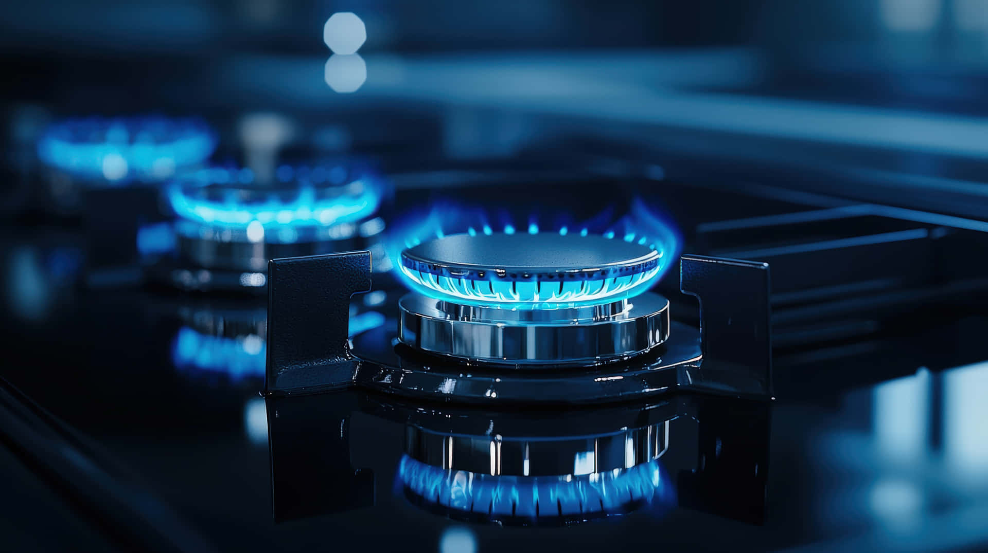 Blue Gas Stove Flames Burning on Modern Cooktop 壁紙 — 一個點燃的瓦斯爐頭的特寫，在深色反光表面上發出鮮豔的藍色火焰。